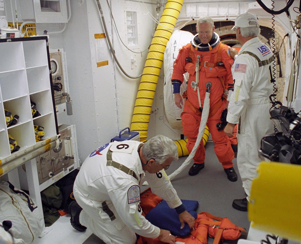KENNEDY SPACE CENTER, FLA. --   In the White Room on Launch Pad 39A, members of the closeout crew help STS-117Mission Specialist Patrick Forrester secure his equipment before climbing into Space Shuttle Atlantis.  The mission to the International Space Station is scheduled to launch at 7:38 p.m. EDT.  Members of the closeout crew help the astronauts don a parachute pack, strap them into the space shuttle's crew module and take care of any other last-minute needs that arise. The White Room is at the end of the orbiter access arm that extends from the fixed service structure and provides entry into the orbiter. The shuttle is delivering a new segment to the starboard side of the space station's backbone, known as the truss. Three spacewalks are planned to install the S3/S4 truss segment, deploy a set of solar arrays and prepare them for operation. STS-117 is the 118th space shuttle flight, the 21st flight to the station, the 28th flight for Atlantis and the first of four flights planned for 2007.  Photo credit: NASA/Tony Gray & Don Kight