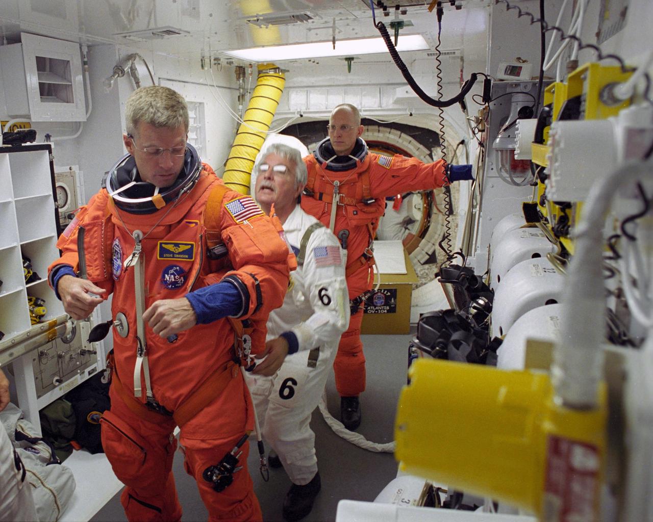 KENNEDY SPACE CENTER, FLA. --   In the White Room on Launch Pad 39A, STS-117 Mission Specialist Steven Swanson is helped by the closeout crew to secure his launch suit before climbing into Space Shuttle Atlantis. Behind Swanson is astronaut Clayton Anderson, waiting his turn.  Anderson is joining the Expedition 15 crew on the International Space Station; Flight Engineer Suni Williams will return to Earth in his place. The mission to the space station is scheduled to launch at 7:38 p.m. EDT.  Members of the closeout crew help the astronauts don a parachute pack, strap them into the space shuttle's crew module and take care of any other last-minute needs that arise. The White Room is at the end of the orbiter access arm that extends from the fixed service structure and provides entry into the orbiter. The shuttle is delivering a new segment to the starboard side of the space station's backbone, known as the truss. Three spacewalks are planned to install the S3/S4 truss segment, deploy a set of solar arrays and prepare them for operation. STS-117 is the 118th space shuttle flight, the 21st flight to the station, the 28th flight for Atlantis and the first of four flights planned for 2007.  Photo credit: NASA/Tony Gray & Don Kight