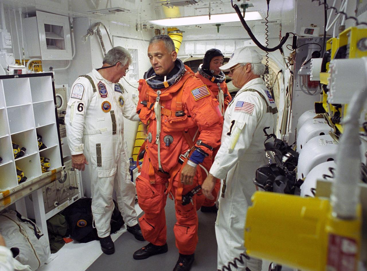 KENNEDY SPACE CENTER, FLA. --    In the White Room on Launch Pad 39A, STS-117 Mission Specialist John "Danny" Olivas is helped by the closeout crew to secure his launch suit before climbing into Space Shuttle Atlantis. Behind Olivas is Pilot Lee Archambault.  The mission to the International Space Station is scheduled to launch at 7:38 p.m. EDT.   Members of the closeout crew help the astronauts don a parachute pack, strap them into the space shuttle's crew module and take care of any other last-minute needs that arise. The White Room is at the end of the orbiter access arm that extends from the fixed service structure and provides entry into the orbiter. The shuttle is delivering a new segment to the starboard side of the space station's backbone, known as the truss. Three spacewalks are planned to install the S3/S4 truss segment, deploy a set of solar arrays and prepare them for operation. STS-117 is the 118th space shuttle flight, the 21st flight to the station, the 28th flight for Atlantis and the first of four flights planned for 2007.  Photo credit: NASA/Tony Gray & Don Kight