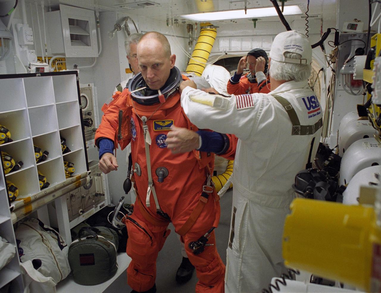 KENNEDY SPACE CENTER, FLA. --    In the White Room on Launch Pad 39A, astronaut Clayton Anderson is helped by the closeout crew to secure his launch suit before climbing into Space Shuttle Atlantis. Anderson is flying to the International Space Station with the STS-117 crew to join the Expedition 15 crew on the space station.  Flight Engineer Suni Williams will return to Earth in his place. The mission to the space station is scheduled to launch at 7:38 p.m. EDT.  Members of the closeout crew help the astronauts don a parachute pack, strap them into the space shuttle's crew module and take care of any other last-minute needs that arise. The White Room is at the end of the orbiter access arm that extends from the fixed service structure and provides entry into the orbiter. The shuttle is delivering a new segment to the starboard side of the space station's backbone, known as the truss. Three spacewalks are planned to install the S3/S4 truss segment, deploy a set of solar arrays and prepare them for operation. STS-117 is the 118th space shuttle flight, the 21st flight to the station, the 28th flight for Atlantis and the first of four flights planned for 2007.  Photo credit: NASA/Tony Gray & Don Kight