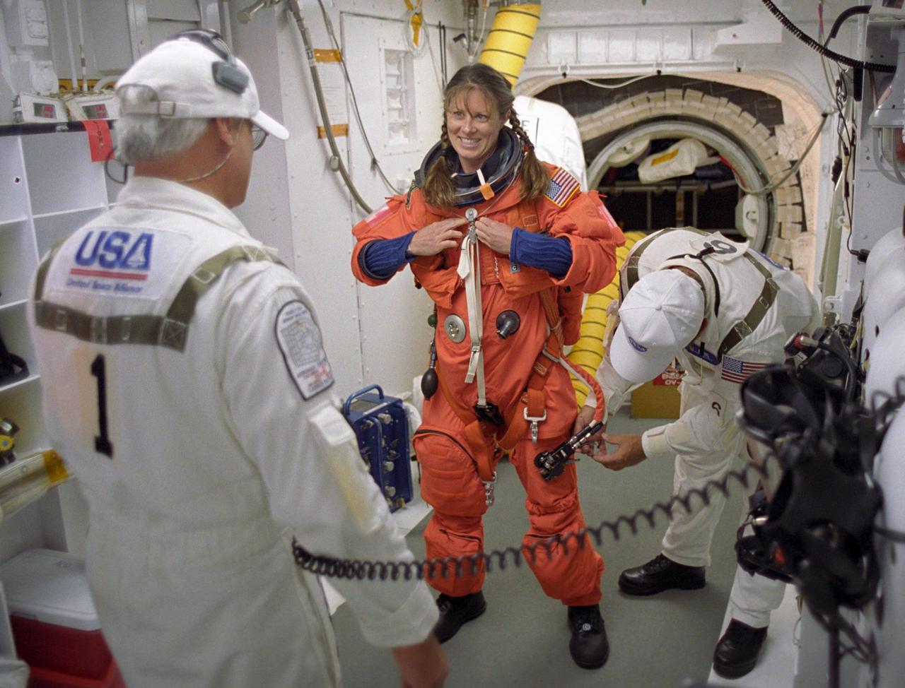 KENNEDY SPACE CENTER, FLA. --   In the White Room on Launch Pad 39A, STS-118 Mission Specialist Tracy Caldwell, with the help of the closeout crew, goes through final preparation of her launch and entry suit before she enters Space Shuttle Endeavour.  The outer end of the orbiter access arm ends in an environmental chamber (the White Room) that mates with the orbiter and allows personnel to enter the crew compartment.  With assistance, each member of the flight crew dons a parachute pack before crawling through the open hatch into the shuttle.  The closeout crew also straps the astronauts into the space shuttle's crew module and takes care of any other last-minute needs that arise.   Space Shuttle Endeavour's STS-118 mission is the 22nd shuttle flight to the International Space Station. It will continue space station construction by delivering a third starboard truss segment, S5, and other payloads such as the SPACEHAB module and the external stowage platform 3.  Liftoff of Endeavour is scheduled at 6:36 p.m. EDT.  Photo credit: NASA/John Kechele, Scott Haun, Tom Farrar