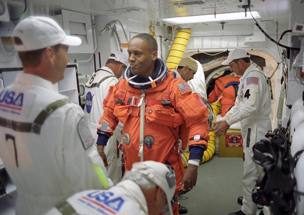 KENNEDY SPACE CENTER, FLA. --   In the White Room on Launch Pad 39A, STS-118 Mission Specialist Alvin Drew is helped with his launch gear by the closeout crew before he enters Space Shuttle Endeavour.  Drew is making his first space flight. The outer end of the orbiter access arm ends in an environmental chamber (the White Room) that mates with the orbiter and allows personnel to enter the crew compartment.  With assistance, each member of the flight crew dons a parachute pack before crawling through the open hatch into the shuttle.  The closeout crew also straps the astronauts into the space shuttle's crew module and takes care of any other last-minute needs that arise.   Space Shuttle Endeavour's STS-118 mission is the 22nd shuttle flight to the International Space Station. It will continue space station construction by delivering a third starboard truss segment, S5, and other payloads such as the SPACEHAB module and the external stowage platform 3.  Liftoff of Endeavour is scheduled at 6:36 p.m. EDT.  Photo credit: NASA/John Kechele, Scott Haun, Tom Farrar