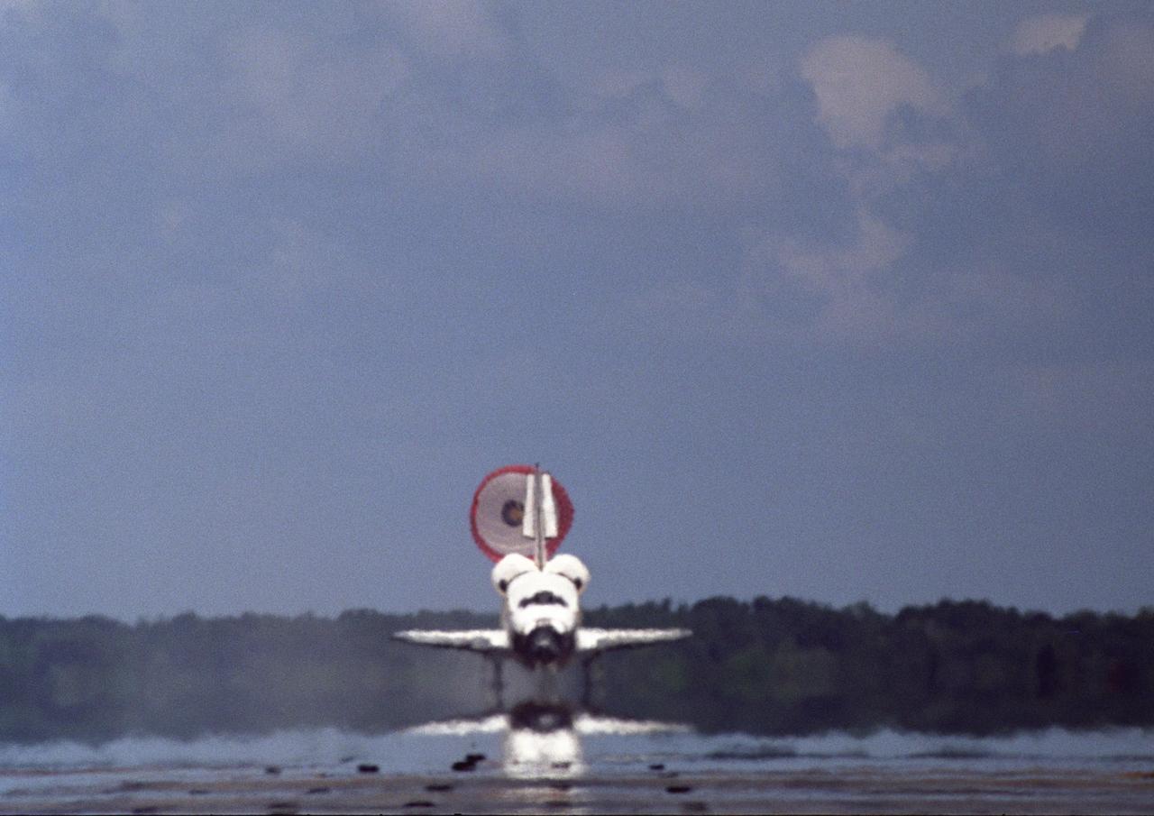 KENNEDY SPACE CENTER, FLA. -- With drag chute sailing behind, Endeavour rolls down runway 15 at NASA's Kennedy Space Center in a picture-perfect landing. The Space Shuttle Endeavour crew, led by Commander Scott Kelly, completes a 13-day mission to the International Space Station.  The STS-118 mission began Aug. 8 and installed a new gyroscope, an external spare parts platform and another truss segment to the expanding station.  Endeavour's main gear touched down at 12:32:16  p.m. EDT.  Nose gear touchdown was at 12:32:29 p.m. and wheel stop was at 12:33:20 p.m.  Endeavour traveled nearly 5.3 million miles, landing on orbit 201.  STS-118 was the 119th space shuttle flight, the 22nd flight to the station, the 20th flight for Endeavour and the second of four missions planned for 2007. This was the 65th landing of an orbiter at Kennedy.  Photo credit: NASA/John Kechele, Scott Haun