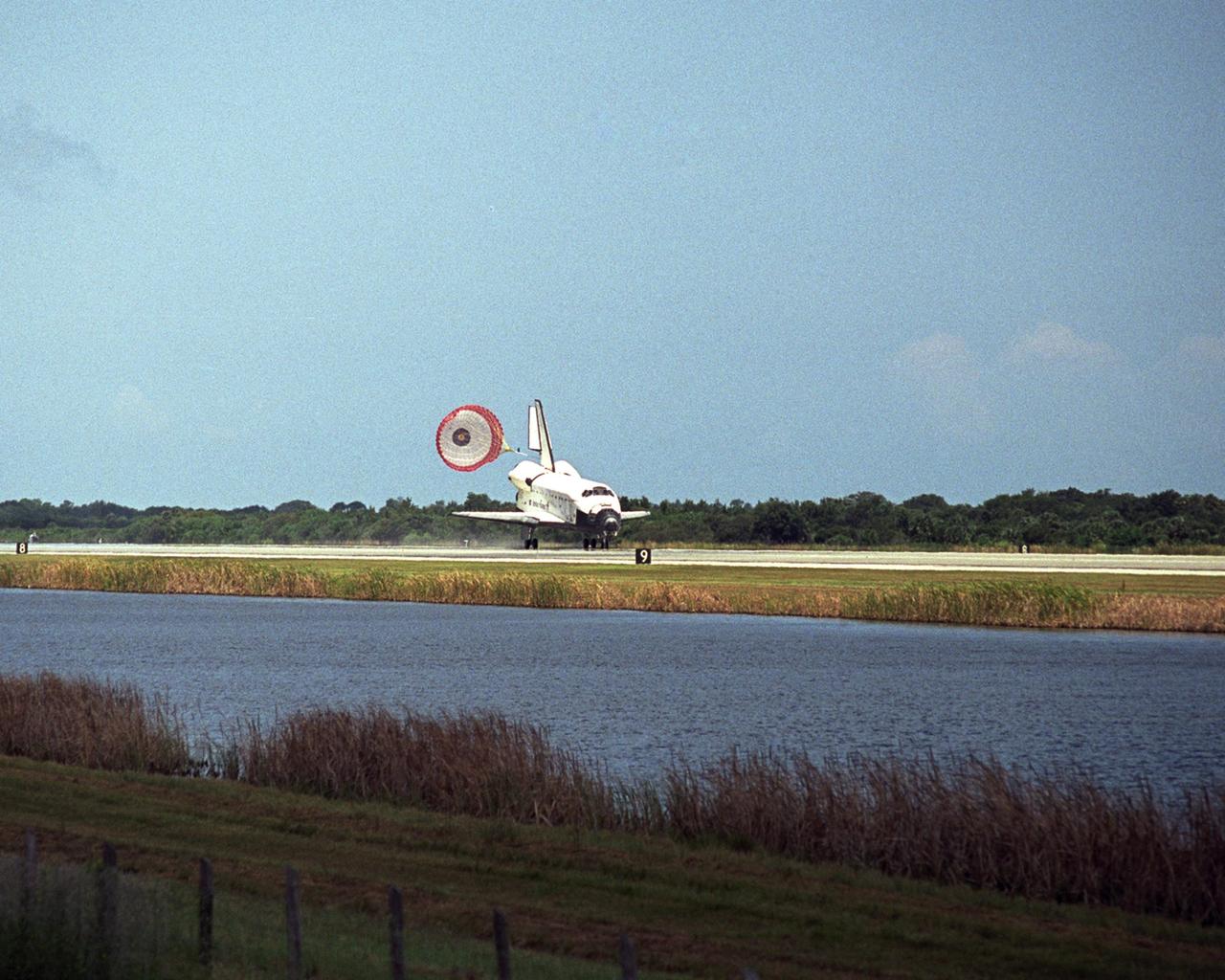 KENNEDY SPACE CENTER, FLA. -- Blue sky and blue water sandwich Endeavour as it rolls to a stop with the aid of a drag chute on runway 15 at NASA's Kennedy Space Center.  The landing completes mission STS-118  to the International Space Station. The mission began Aug. 8 and installed a new gyroscope, an external spare parts platform and another truss segment to the expanding station.  Endeavour's main gear touched down at 12:32:16  p.m. EDT.  Nose gear touchdown was at 12:32:29 p.m. and wheel stop was at 12:33:20 p.m.  Endeavour traveled nearly 5.3 million miles, landing on orbit 201.  STS-118 was the 119th space shuttle flight, the 22nd flight to the station, the 20th flight for Endeavour and the second of four missions planned for 2007. This was the 65th landing of an orbiter at Kennedy.  Photo credit: NASA/Tony Gray