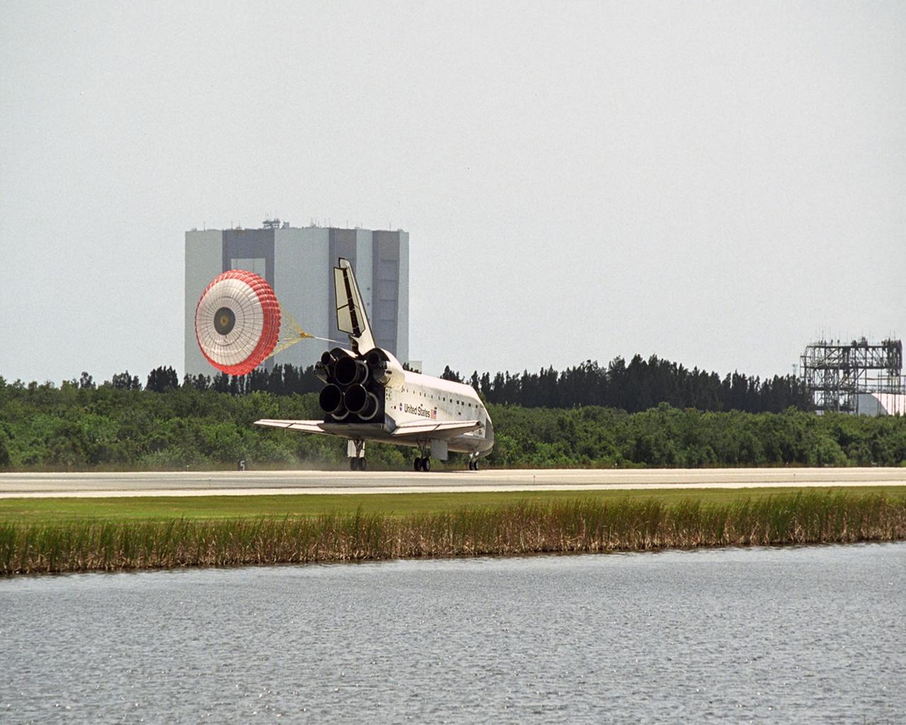 KENNEDY SPACE CENTER, FLA. -- With drag chute sailing behind, Endeavour rolls down runway 15 at NASA's Kennedy Space Center, completing the 13-day STS-118 mission to the International Space Station. Behind it is the looming Vehicle Assembly Building, which stands 525-feet tall.  The mission began Aug. 8 and installed a new gyroscope, an external spare parts platform and another truss segment to the expanding station.  Endeavour's main gear touched down at 12:32:16  p.m. EDT.  Nose gear touchdown was at 12:32:29 p.m. and wheel stop was at 12:33:20 p.m.  Endeavour traveled nearly 5.3 million miles, landing on orbit 201.  STS-118 was the 119th space shuttle flight, the 22nd flight to the station, the 20th flight for Endeavour and the second of four missions planned for 2007. This was the 65th landing of an orbiter at Kennedy.  Photo credit: NASA/Regina Mitchell-Ryall, Robert Murray