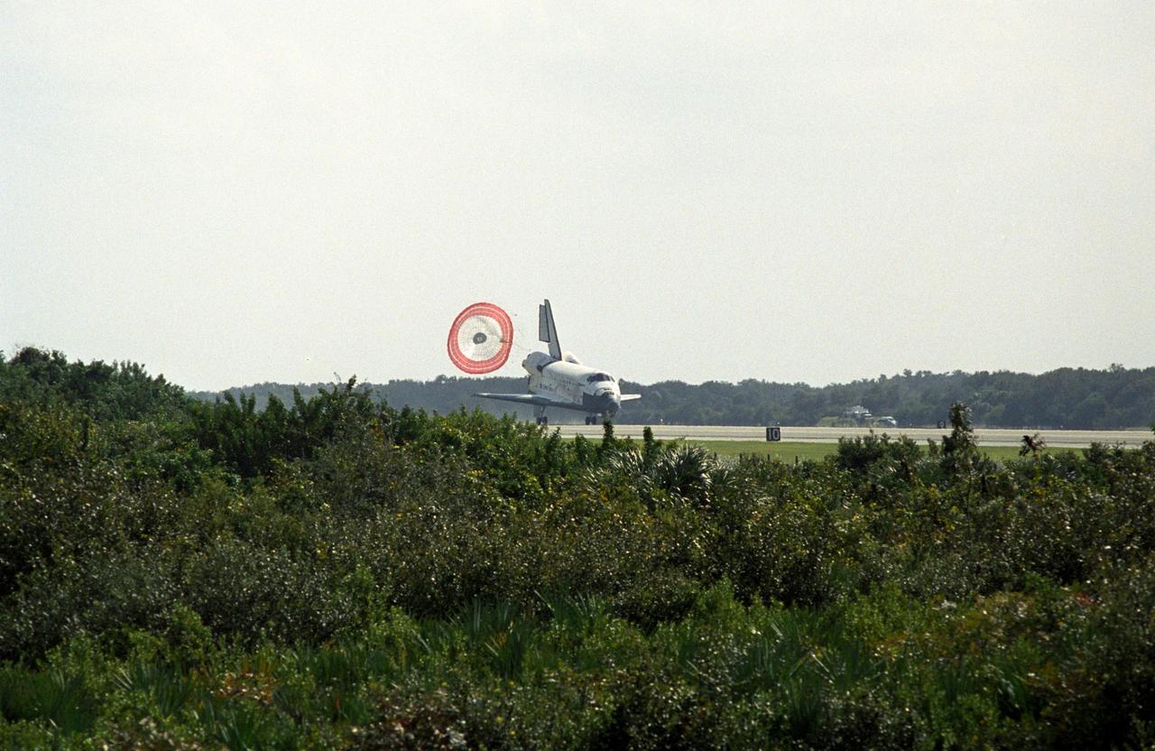 KENNEDY SPACE CENTER, FLA. -- Viewed over the scrub near Runway 33 of the Shuttle Landing Facility at NASA's Kennedy Space Center, space shuttle Discovery is slowed by a drag chute behind it as it lands.  The landing completes the 15-day mission STS-120 to the International Space Station. Main gear touchdown was 1:01:16 p.m.  Wheel stop was at 1:02:07 p.m.  Mission elapsed time was 15 days, 2 hours, 24 minutes and 2 seconds.  During the mission, the STS-120 crew continued the construction of the station with the installation of the Harmony Node 2 module and the relocation of the P6 truss.  Photo credit: NASA/Sandra Joseph, Tim Powers