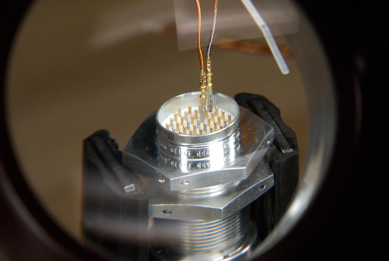 KENNEDY SPACE CENTER, FLA. -- At a lab at NASA's Kennedy Space Center, the first two of nine pins have been soldered to the socket of the replacement feed-through connector that will be installed in the external fuel tank for space shuttle Atlantis' STS-122 mission. Two United Launch Alliance technicians, who performed this exacting task on the Centaur upper stage for Atlas and Titan launches in 1994, will be doing the soldering. Soldering the connector pins and sockets together addresses the most likely cause of a problem in the engine cutoff sensor system, or ECO system. Some of the tank's ECO sensors failed during propellant tanking for launch attempts on Dec. 6 and Dec. 9. Results of a tanking test on Dec. 18 pointed to an open circuit in the feed-through connector wiring, which is located at the base of the tank. The feed-through connector passes the wires from the inside of the tank to the outside. After the soldering is completed and the connector is reinstalled, shuttle program managers will decide on how to proceed. The launch date for mission STS-122 is under review. Photo credit: NASA/Kim Shiflett