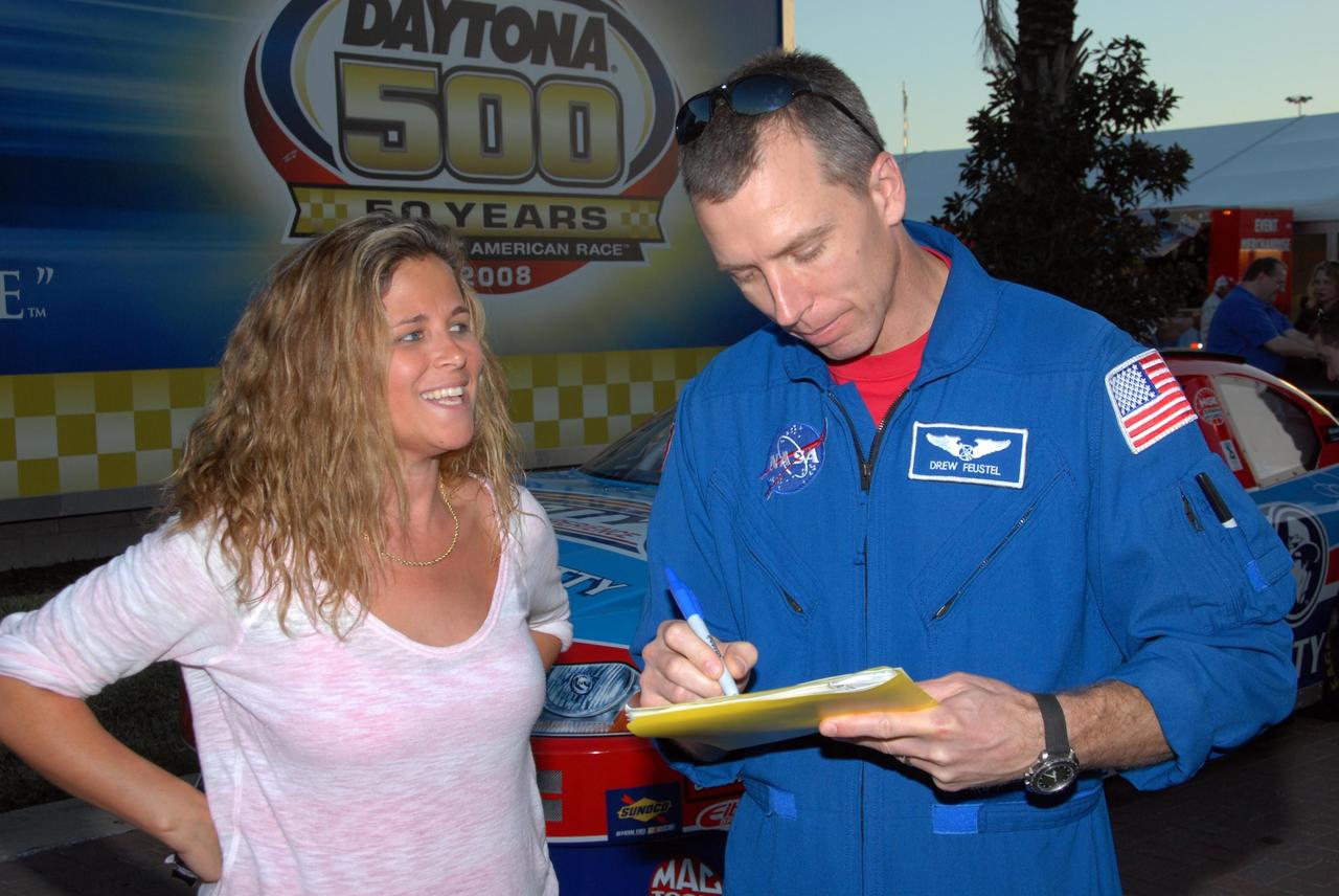 KENNEDY SPACE CENTER, FLA. -- Astronaut Andrew Feustel gives an autograph to a fan during NASCAR's Preseason Thunder Fan Fest at the Daytona International Speedway. Feustel's appearance celebrates NASA's 50th anniversary and the speedway's 50th running of the Daytona 500 in February. The NASA/NASCAR association spans decades. Technology developed for the space program has helped NASCAR drivers increase their performance and stay safe over the years. They wear cooling suits similar to what astronauts wear during a spacewalk. Foam that NASA developed for aircraft seats protects racecar drivers' necks in crashes. In addition to participating in the fan festival, NASA will fly three Daytona 500 flags aboard an upcoming space shuttle flight. Speedway officials plan to wave one of the flags to begin the 2008 installment of the Daytona 500, while another will be presented to the winning driver. NASA will keep the third. Feustel will fly on the space shuttle mission STS-125 to the Hubble Space Telescope. The mission will extend and improve the observatory's capabilities through 2013. Launch is targeted for August 2008. Photo credit: NASA/George Shelton