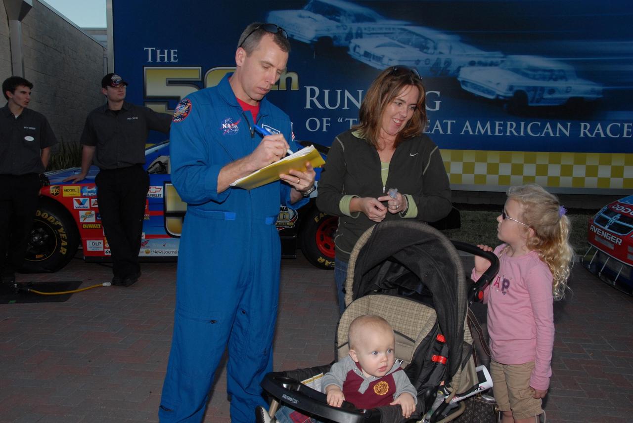 KENNEDY SPACE CENTER, FLA. -- Astronaut Andrew Feustel gives an autograph to a fan during NASCAR's Preseason Thunder Fan Fest at the Daytona International Speedway. Feustel's appearance celebrates NASA's 50th anniversary and the speedway's 50th running of the Daytona 500 in February. The NASA/NASCAR association spans decades. Technology developed for the space program has helped NASCAR drivers increase their performance and stay safe over the years. They wear cooling suits similar to what astronauts wear during a spacewalk. Foam that NASA developed for aircraft seats protects racecar drivers' necks in crashes. In addition to participating in the fan festival, NASA will fly three Daytona 500 flags aboard an upcoming space shuttle flight. Speedway officials plan to wave one of the flags to begin the 2008 installment of the Daytona 500, while another will be presented to the winning driver. NASA will keep the third. Feustel will fly on the space shuttle mission STS-125 to the Hubble Space Telescope. The mission will extend and improve the observatory's capabilities through 2013. Launch is targeted for August 2008. Photo credit: NASA/George Shelton