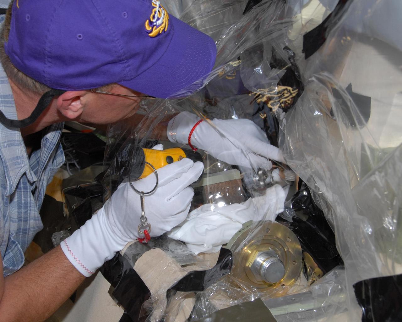 KENNEDY SPACE CENTER, FLA. --  Mike Berger, with Lockheed Martin, examines the internal connector on space shuttle Atlantis' external tank to which the replacement feed-through connector in the engine cutoff, or ECO, sensor system will be attached.   The replacement connector is seen below Berger's hand.  The feed-through connector passes the wires from the inside of the tank to the outside.  Results of a tanking test on Dec. 18 pointed to an open circuit in the feed-through connector wiring, which is located at the base of the tank. The pins in the replacement connector have been precisely soldered to create a connection that allows sensors inside the tank to send signals to the computers onboard Atlantis. The work is being done on Launch Pad 39A.   Space shuttle Atlantis is now targeted for launch on Feb. 7.  Photo credit: NASA/George Shelton