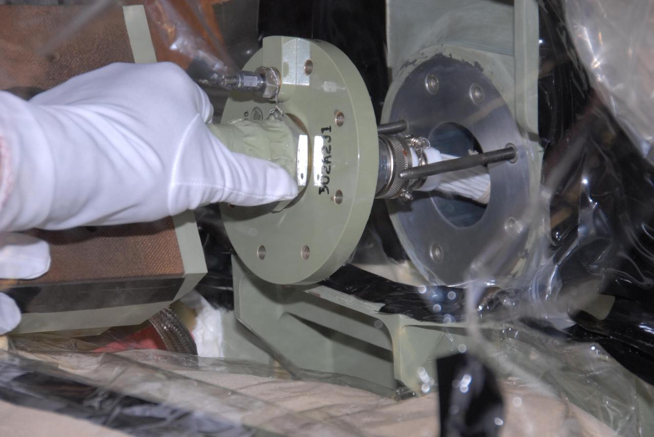 KENNEDY SPACE CENTER, FLA. --   Lloyd Johns, with Lockheed Martin, attaches the replacement feed-through connector in the engine cutoff, or ECO, sensor system to the internal connector on space shuttle Atlantis' external tank. The feed-through connector passes the wires from the inside of the tank to the outside.  Results of a tanking test on Dec. 18 pointed to an open circuit in the feed-through connector wiring, which is located at the base of the tank. The pins in the replacement connector have been precisely soldered to create a connection that allows sensors inside the tank to send signals to the computers onboard Atlantis. The work is being done on Launch Pad 39A.   Space shuttle Atlantis is now targeted for launch on Feb. 7.  Photo credit: NASA/George Shelton