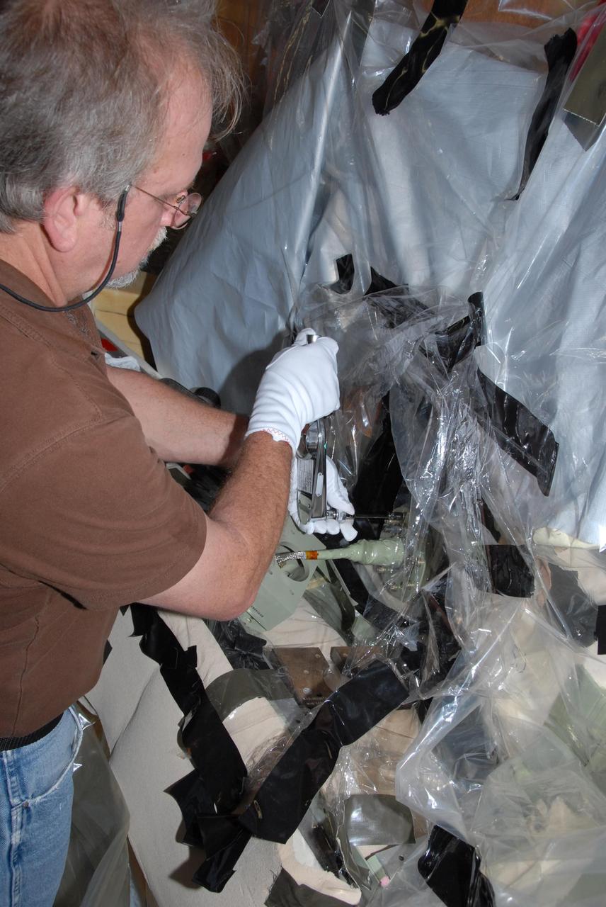 KENNEDY SPACE CENTER, FLA. --    Ray Clark, a Lockheed Martin engineer, completes attaching the replacement feed-through connector in the engine cutoff, or ECO, sensor system to the internal connector on space shuttle Atlantis' external tank. The feed-through connector passes the wires from the inside of the tank to the outside.  Results of a tanking test on Dec. 18 pointed to an open circuit in the feed-through connector wiring, which is located at the base of the tank. The pins in the replacement connector have been precisely soldered to create a connection that allows sensors inside the tank to send signals to the computers onboard Atlantis. The work is being done on Launch Pad 39A.   Space shuttle Atlantis is now targeted for launch on Feb. 7.  Photo credit: NASA/George Shelton