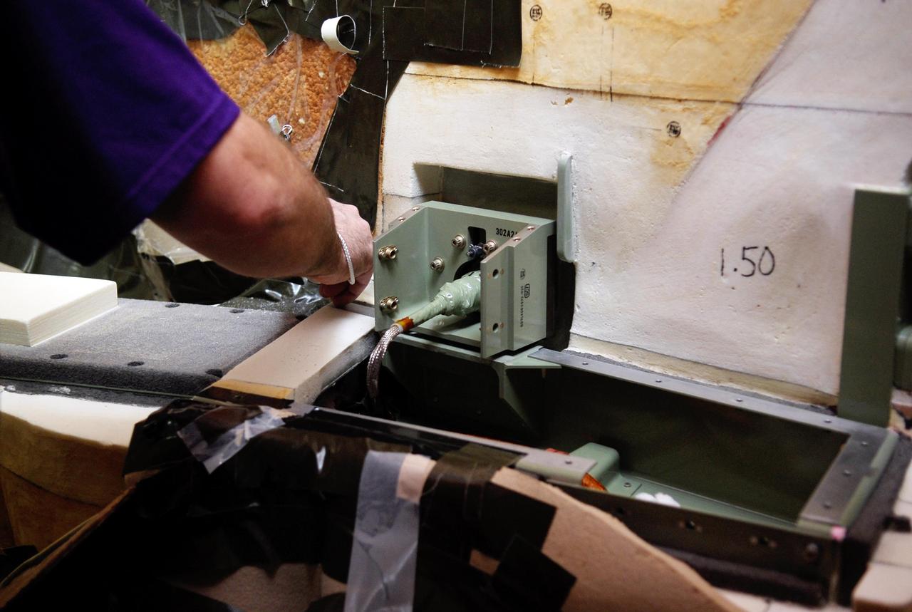 KENNEDY SPACE CENTER, FLA. -- On Launch Pad 39A at NASA's Kennedy Space Center, foam insulation is being trimmed for placement around the engine cutoff, or ECO, sensor system connector and wiring on space shuttle Atlantis' external tank.  The foam was removed to enable engineers to remove and replace a feed-through ECO sensor connector on the tank.  The feed-through connector passes the wires from the inside of the tank to the outside.  Results of a tanking test on Dec. 18 pointed to an open circuit in the feed-through connector wiring, which is located at the base of the tank. The pins in the replacement connector were precisely soldered to create a connection that allows sensors inside the tank to send signals to the computers onboard Atlantis.  The launch date for the shuttle's STS-122 mission has now been targeted for Feb. 7.  Photo credit: NASA/Kim Shiflett