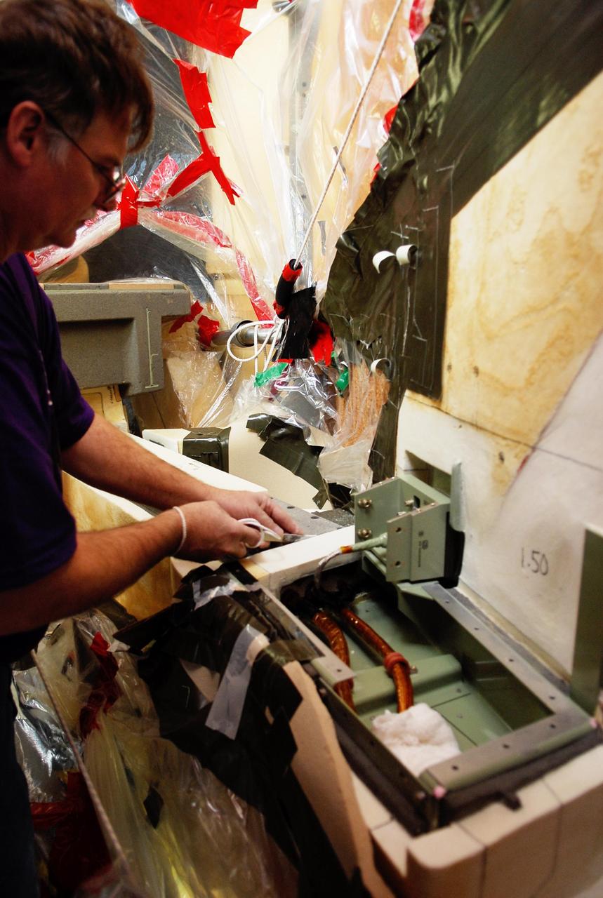 KENNEDY SPACE CENTER, FLA. -- On Launch Pad 39A at NASA's Kennedy Space Center, foam insulation is being trimmed for placement around the engine cutoff, or ECO, sensor system connector and wiring on space shuttle Atlantis' external tank.  The foam was removed to enable engineers to remove and replace a feed-through ECO sensor connector on the tank.  The feed-through connector passes the wires from the inside of the tank to the outside.  Results of a tanking test on Dec. 18 pointed to an open circuit in the feed-through connector wiring, which is located at the base of the tank. The pins in the replacement connector were precisely soldered to create a connection that allows sensors inside the tank to send signals to the computers onboard Atlantis.  The launch date for the shuttle's STS-122 mission has now been targeted for Feb. 7.  Photo credit: NASA/Kim Shiflett