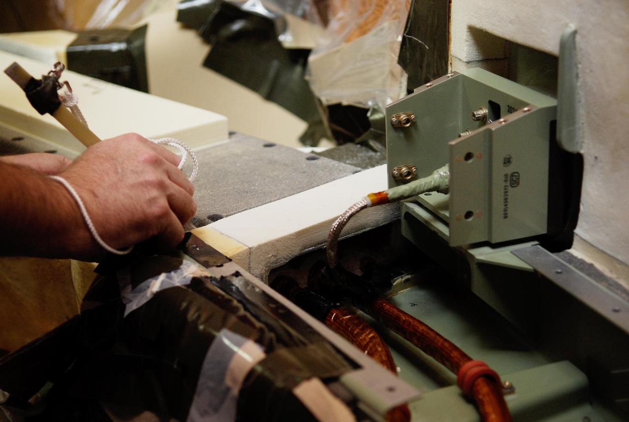 KENNEDY SPACE CENTER, FLA. -- On Launch Pad 39A at NASA's Kennedy Space Center, foam insulation is being trimmed for placement around the engine cutoff, or ECO, sensor system connector and wiring on space shuttle Atlantis' external tank.  The foam was removed to enable engineers to remove and replace a feed-through ECO sensor connector on the tank.  The feed-through connector passes the wires from the inside of the tank to the outside.  Results of a tanking test on Dec. 18 pointed to an open circuit in the feed-through connector wiring, which is located at the base of the tank. The pins in the replacement connector were precisely soldered to create a connection that allows sensors inside the tank to send signals to the computers onboard Atlantis.  The launch date for the shuttle's STS-122 mission has now been targeted for Feb. 7.  Photo credit: NASA/Kim Shiflett
