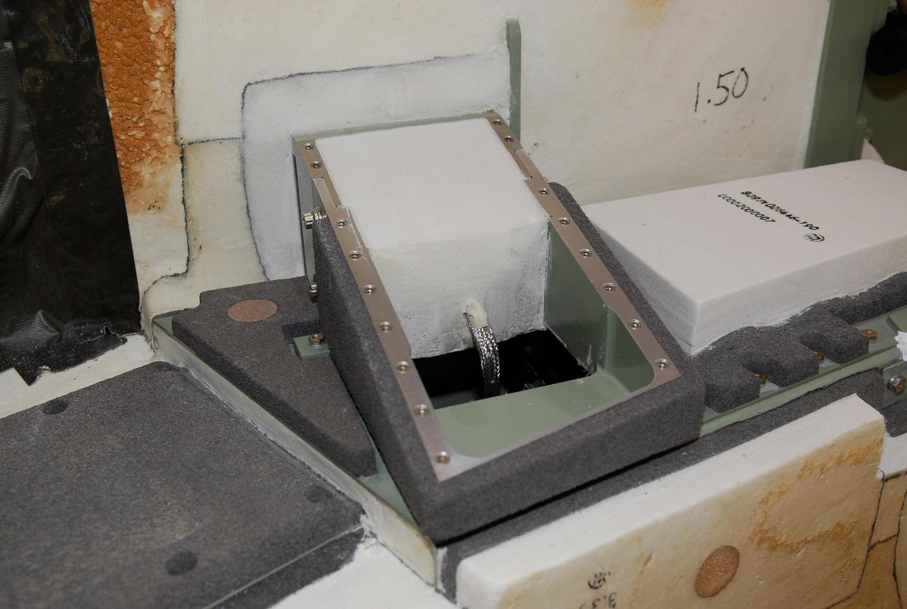 KENNEDY SPACE CENTER, FLA. --   On Launch Pad 39A at NASA's Kennedy Space Center, foam is being replaced around the engine cutoff, or ECO, sensor system connector and wiring on space shuttle Atlantis' external tank.  The foam was removed to enable engineers to remove and replace a feed-through ECO sensor connector on the tank.  The feed-through connector passes the wires from the inside of the tank to the outside.  Results of a tanking test on Dec. 18 pointed to an open circuit in the feed-through connector wiring, which is located at the base of the tank. The pins in the replacement connector were precisely soldered to create a connection that allows sensors inside the tank to send signals to the computers onboard Atlantis.  The launch date for the shuttle's STS-122 mission has now been targeted for Feb. 7.   Photo credit: NASA/Kim Shiflett