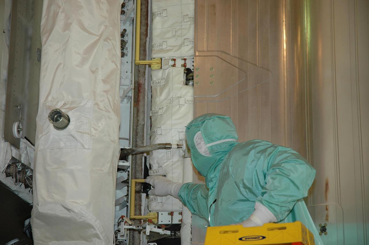 KENNEDY SPACE CENTER, FLA. --  On Launch Pad 39A at NASA's Kennedy Space Center, an engineer checks the progress of payload bay doors closing on space shuttle Atlantis. During launch preparations, technicians noticed a small section of a braided metal hose that was bent in a shape similar to the Greek letter Omega. The radiator retract hose, part of the shuttle's cooling system that carries Freon, is designed to flex. Engineers designed a tool to guide the hose back into the storage box. During the starboard door closure, eight incremental stops were performed. After each stop, the aft hose was adjusted and seated in place utilizing the ladder and hose assist tool. The team was satisfied with the final placement of the hose at door closure. STS-122 is the 121st space shuttle flight, the 29th flight for Atlantis and the 24th flight to the International Space Station. The Columbus laboratory module, built by the European Space Agency, is approximately 23 feet long and 15 feet wide, allowing it to hold 10 large racks of experiments. Atlantis is scheduled to launch at 2:45 p.m. Feb. 7.  Photo credit: NASA/Jack Pfaller