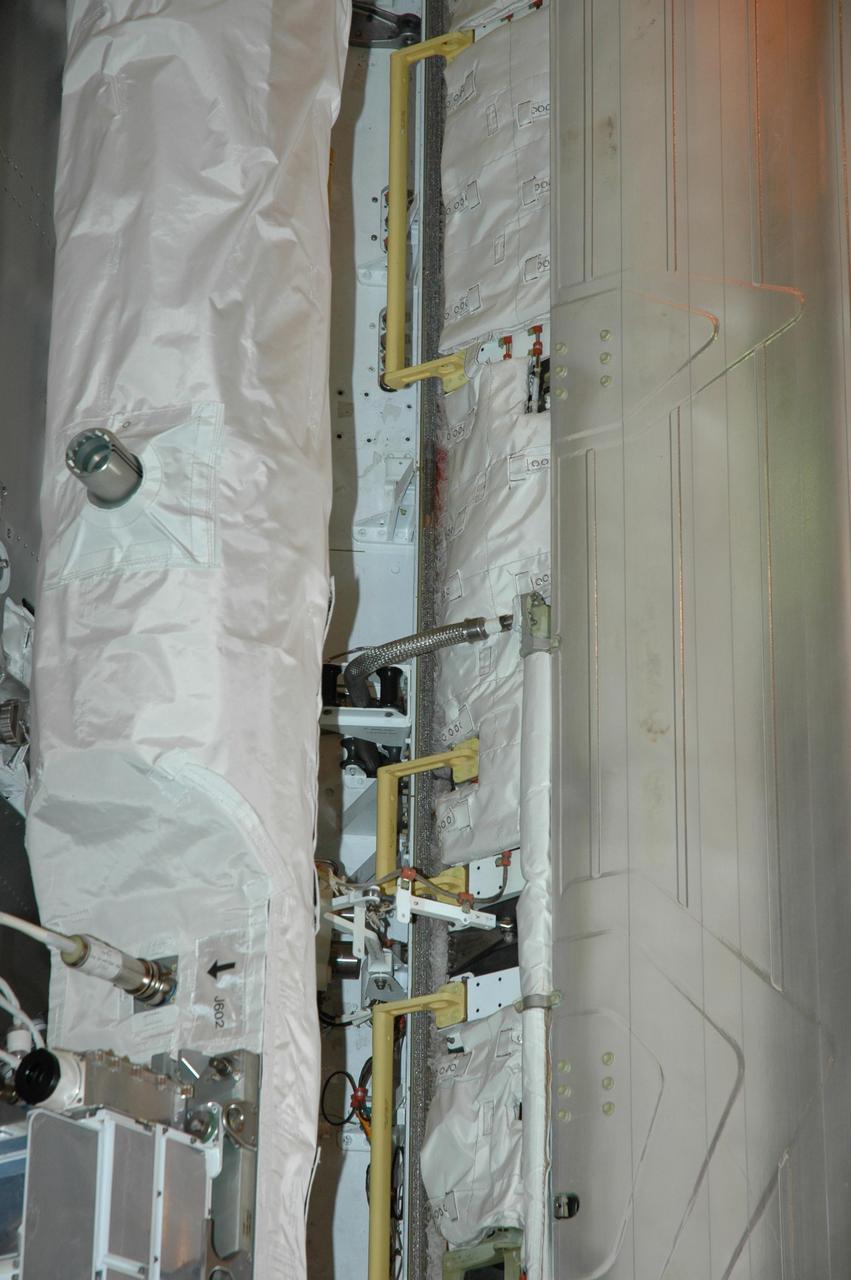 KENNEDY SPACE CENTER, FLA. --  On Launch Pad 39A at NASA's Kennedy Space Center, the payload bay doors are closing on space shuttle Atlantis.  During launch preparations, technicians noticed a small section of a braided metal hose that was bent in a shape similar to the Greek letter Omega. The radiator retract hose (seen in the middle), part of the shuttle's cooling system that carries Freon, is designed to flex. Engineers designed a tool to guide the hose back into the storage box. During the starboard door closure, eight incremental stops were performed. After each stop, the aft hose was adjusted and seated in place utilizing the ladder and hose assist tool. The team was satisfied with the final placement of the hose at door closure.  STS-122 is the 121st space shuttle flight, the 29th flight for Atlantis and the 24th flight to the International Space Station. The Columbus laboratory module, built by the European Space Agency, is approximately 23 feet long and 15 feet wide, allowing it to hold 10 large racks of experiments. Atlantis is scheduled to launch at 2:45 p.m. Feb. 7.  Photo credit: NASA/Jack Pfaller
