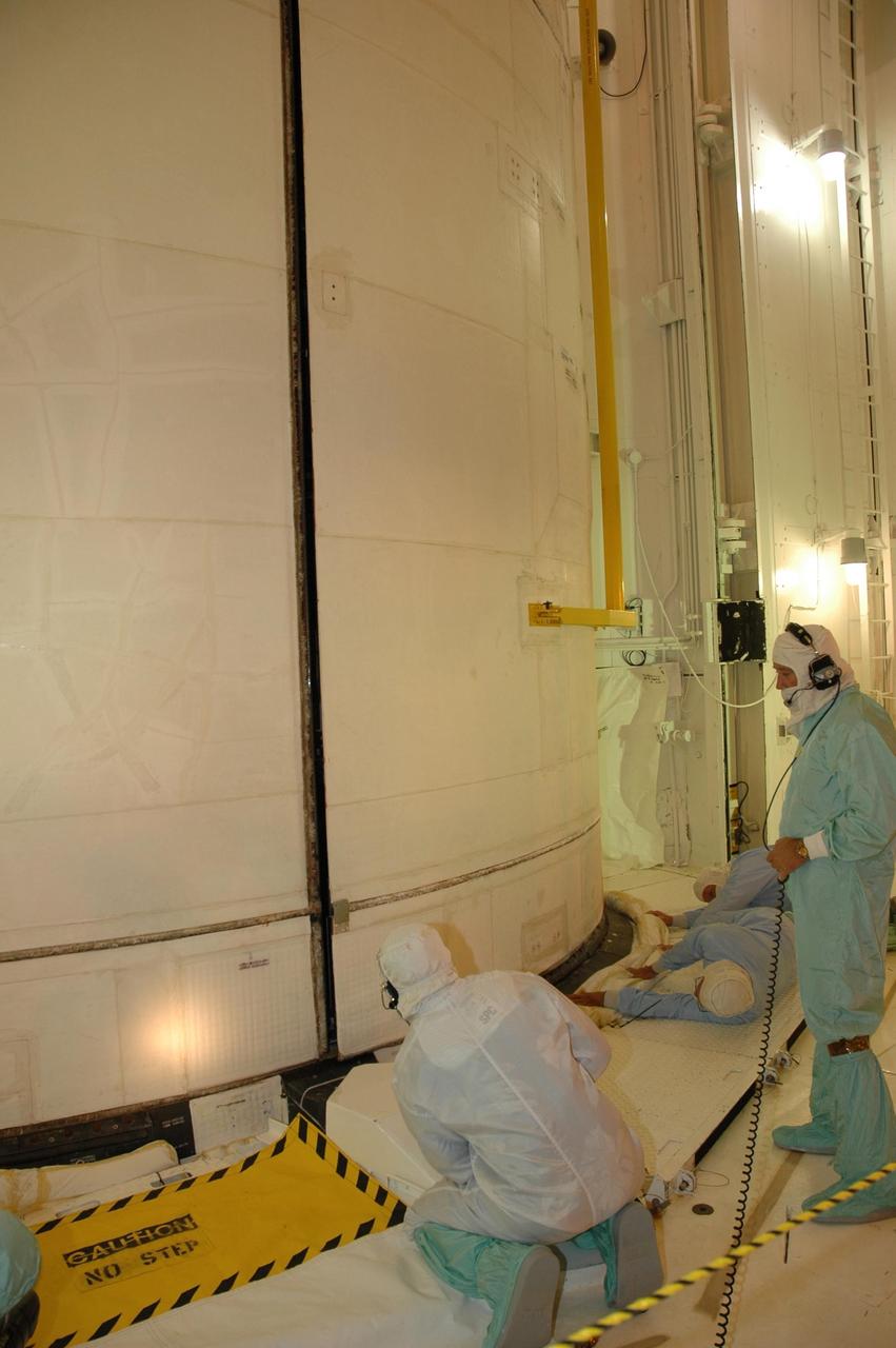 KENNEDY SPACE CENTER, FLA. --   On Launch Pad 39A at NASA's Kennedy Space Center, engineers examine the fit of the payload bay doors on space shuttle Atlantis as they are closing.  During launch preparations, technicians noticed a small section of a braided metal hose that was bent in a shape similar to the Greek letter Omega. The radiator retract hose (seen in the middle), part of the shuttle's cooling system that carries Freon, is designed to flex. Engineers designed a tool to guide the hose back into the storage box. During the starboard door closure, eight incremental stops were performed. After each stop, the aft hose was adjusted and seated in place utilizing the ladder and hose assist tool. The team was satisfied with the final placement of the hose at door closure.  STS-122 is the 121st space shuttle flight, the 29th flight for Atlantis and the 24th flight to the International Space Station. The Columbus laboratory module, built by the European Space Agency, is approximately 23 feet long and 15 feet wide, allowing it to hold 10 large racks of experiments. Atlantis is scheduled to launch at 2:45 p.m. Feb. 7.  Photo credit: NASA/Jack Pfaller