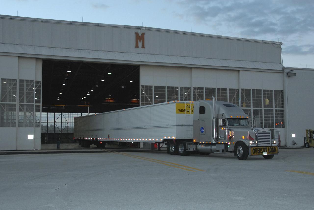 KENNEDY SPACE CENTER, FLA. -- The truck carrying the United Launch Alliance Delta II first stage backs into Hangar M on Cape Canaveral Air Force Station in Florida.  The Delta rocket will be used to launch the Gamma-Ray Large Area Space Telescope, or GLAST, in May from Launch Pad 17-B on CCAFS.  The GLAST is a powerful space observatory that will explore the Universe's ultimate frontier, where nature harnesses forces and energies far beyond anything possible on Earth;  probe some of science's deepest questions, such as what our Universe is made of, and search for new laws of physics; explain how black holes accelerate jets of material to nearly light speed; and help crack the mystery of stupendously powerful explosions known as gamma-ray bursts.   Photo credit: NASA/George Shelton