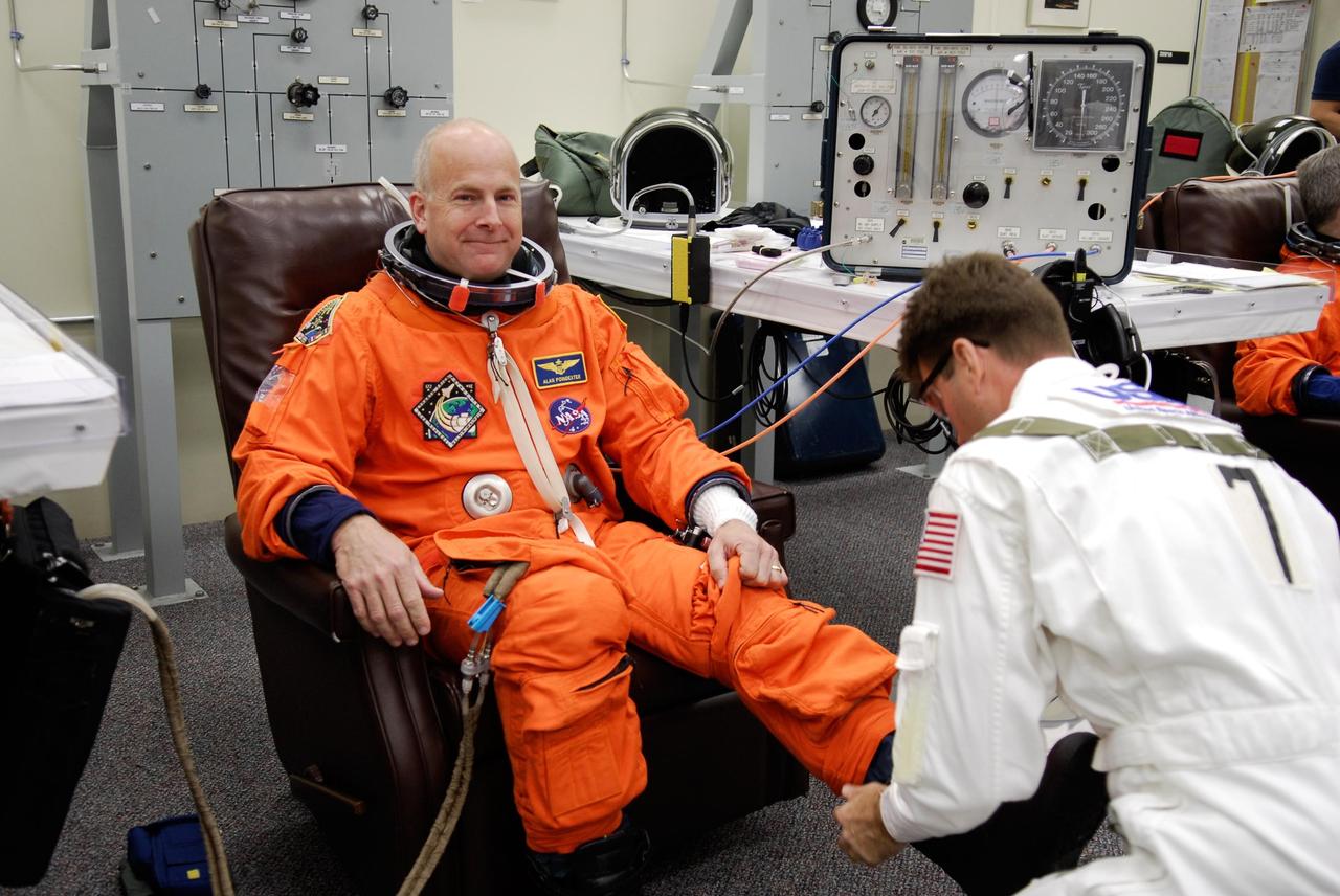 KENNEDY SPACE CENTER, FLA. -- Pilot Alan Poindexter is helped with his boots while donning his launch and entry suit for launch of space shuttle Atlantis on the STS-122 mission. The launch, scheduled for 2:45 p.m. EST, will be the third attempt for Atlantis since December 2007 to carry the European Space Agency's Columbus laboratory to the International Space Station. During the 11-day mission, the crew's prime objective is to attach the laboratory to the Harmony module, adding to the station's size and capabilities. Photo credit: NASA/Kim Shiflett