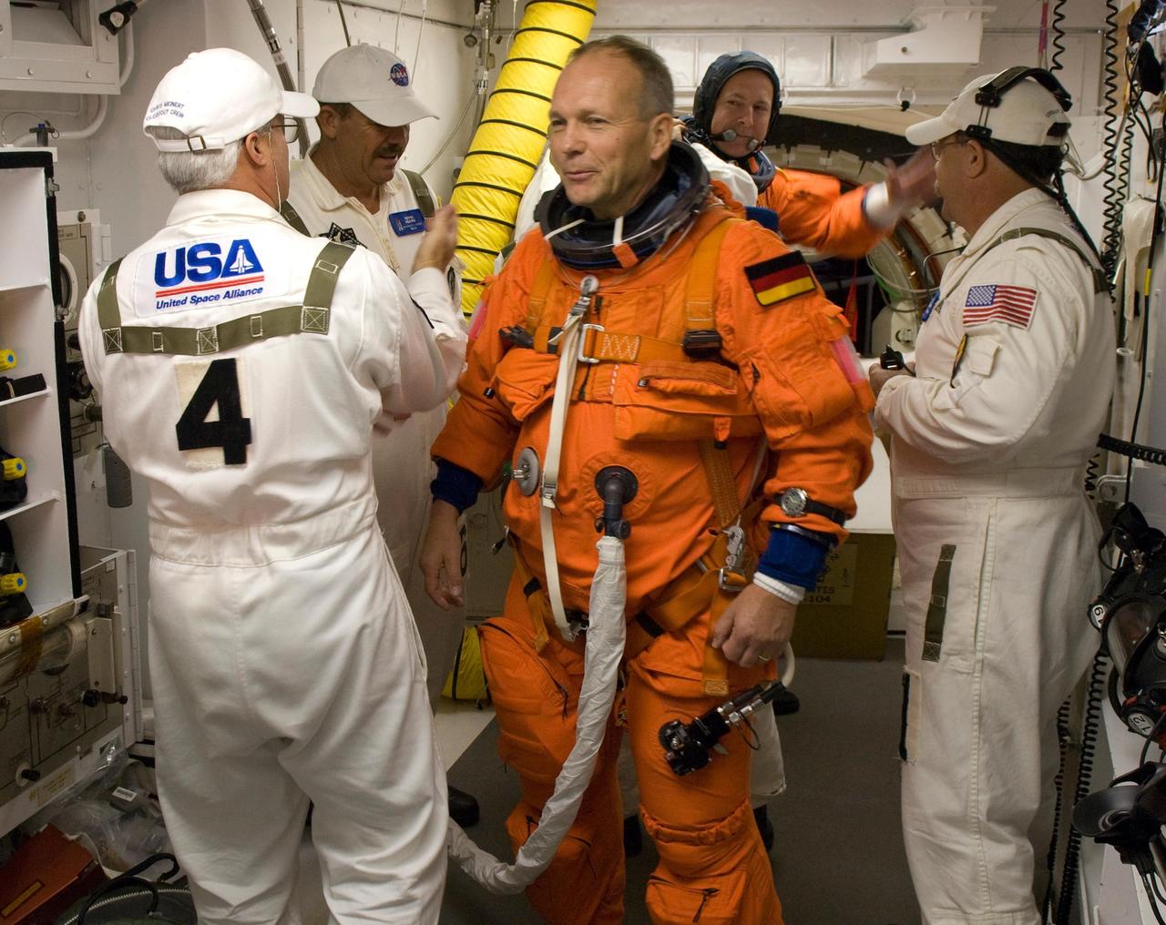 KENNEDY SPACE CENTER, FLA. -- In the White Room on Launch Pad 39A at NASA's Kennedy Space Center, the closeout crew helps STS-122 Mission Specialist Hans Schlegel with his launch and entry suit before entering space shuttle Atlantis for liftoff at 2:45 p.m. EST. Schlegel, who represents the European Space Agency, is making his second shuttle flight. Behind Schlegel is Pilot Alan Poindexter. The launch will be the third attempt for Atlantis since December 2007 to carry the European Space Agency's Columbus laboratory to the International Space Station. During the 11-day mission, the crew's prime objective is to attach the laboratory to the Harmony module, adding to the station's size and capabilities. Photo credit: NASA/Scott Haun, Rick Prickett