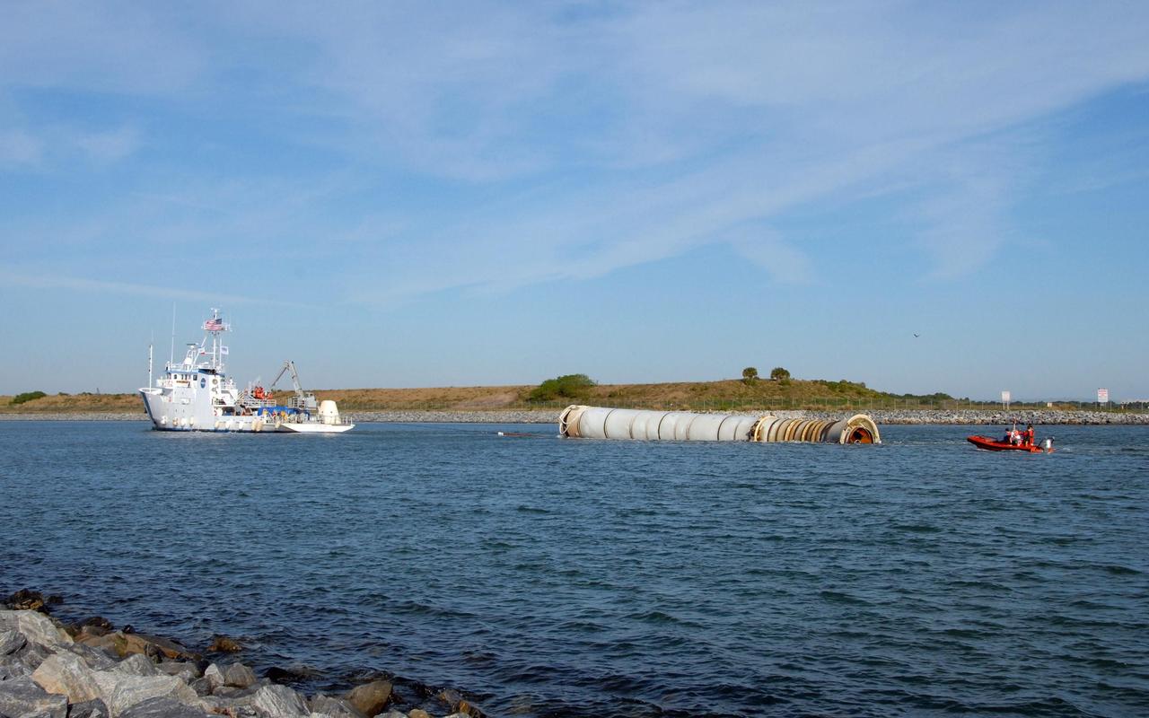 KENNEDY SPACE CENTER, FLA. -- The solid rocket booster retrieval ship Freedom Star tows one of the boosters, retrieved after the launch of space shuttle Atlantis' STS-122 mission, toward Port Canaveral. The space shuttle's solid rocket booster casings and associated flight hardware are recovered at sea. The boosters impact the Atlantic Ocean approximately seven minutes after liftoff. The splashdown area is a square of about 6 by 9 nautical miles located about 140 nautical miles downrange from the launch pad. The retrieval ships are stationed approximately 8 to 10 nautical miles from the impact area at the time of splashdown. As soon as the boosters enter the water, the ships accelerate to a speed of 15 knots and quickly close on the boosters. The pilot chutes and main parachutes are the first items to be brought on board. With the chutes and frustum recovered, attention turns to the boosters. The ship's tow line is connected and the booster is returned to the Port and, after transfer to a position alongside the ship, to Hangar AF at Cape Canaveral Air Force Station. There, the expended boosters are disassembled, refurbished and reloaded with solid propellant for reuse.  Photo credit: NASA/Jack Pfaller