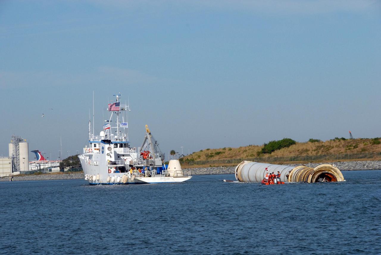 KENNEDY SPACE CENTER, FLA. -- The solid rocket booster retrieval ship Freedom Star tows toward Port Canaveral one of the boosters, retrieved after the launch of space shuttle Atlantis' STS-122 mission, toward Port Canaveral.  The space shuttle's solid rocket booster casings and associated flight hardware are recovered at sea. The boosters impact the Atlantic Ocean approximately seven minutes after liftoff. The splashdown area is a square of about 6 by 9 nautical miles located about 140 nautical miles downrange from the launch pad. The retrieval ships are stationed approximately 8 to 10 nautical miles from the impact area at the time of splashdown. As soon as the boosters enter the water, the ships accelerate to a speed of 15 knots and quickly close on the boosters. The pilot chutes and main parachutes are the first items to be brought on board. With the chutes and frustum recovered, attention turns to the boosters. The ship's tow line is connected and the booster is returned to the Port and, after transfer to a position alongside the ship, to Hangar AF at Cape Canaveral Air Force Station. There, the expended boosters are disassembled, refurbished and reloaded with solid propellant for reuse.  Photo credit: NASA/Jack Pfaller