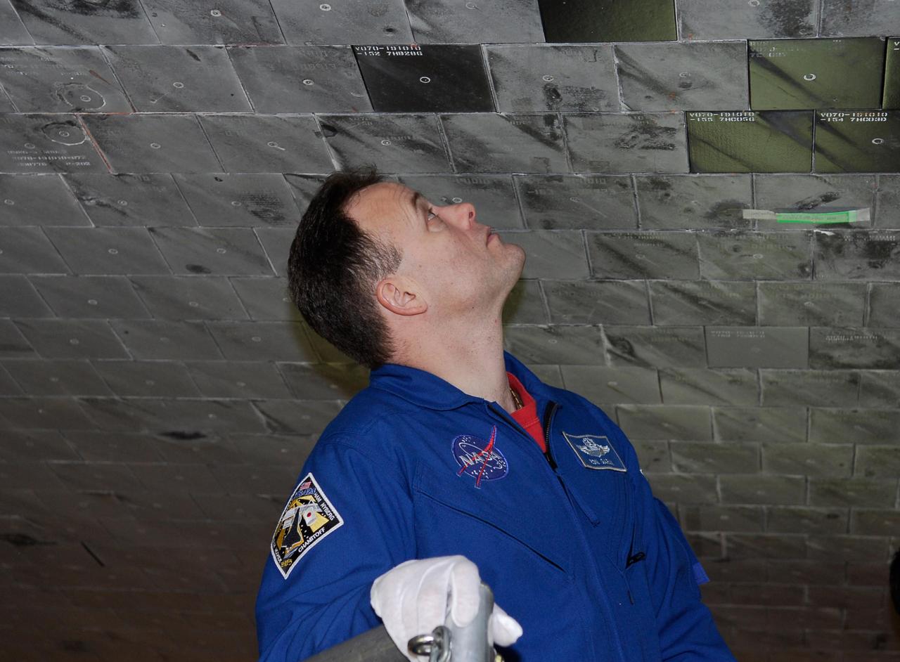 KENNEDY SPACE CENTER, FLA. -- STS-124 Mission Specialist Ron Garan examines the tiles on the underbelly of space shuttle Discovery in the Orbiter Processing Facility bay 2 at NASA's Kennedy Space Center. Members of the crew are at Kennedy for a crew equipment interface test. On the mission, Discovery will transport the Kibo Japanese Experiment Module - Pressurized Module (JEM-PM) and the Japanese Remote Manipulator System (JEM-RMS) to the International Space Station to complete the Kibo laboratory. The launch of Discovery is targeted for April 24. Photo credit: NASA/Kim Shiflett
