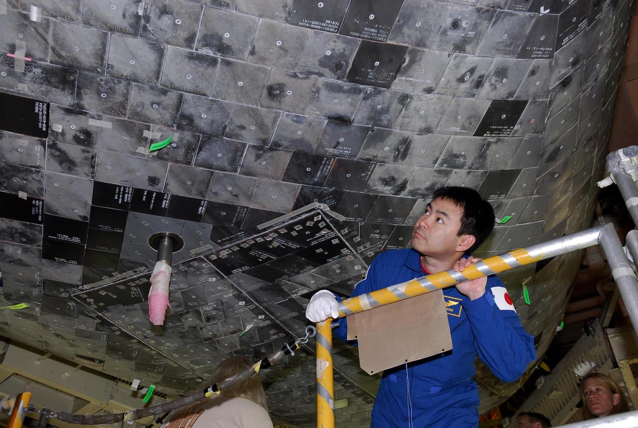 KENNEDY SPACE CENTER, FLA. -- In the Orbiter Processing Facility bay 3 at NASA's Kennedy Space Center, STS-124 Mission Specialist Akihiko Hoshide takes a close look at the tiles on the underbelly of space shuttle Discovery. Hoshide represents the Japan Aerospace Exploration Agency, called JAXA. On the mission, Discovery will transport the Kibo Japanese Experiment Module - Pressurized Module (JEM-PM) and the Japanese Remote Manipulator System (JEM-RMS) to the International Space Station to complete the Kibo laboratory. The launch of Discovery is targeted for April 24. Photo credit: NASA/Kim Shiflett
