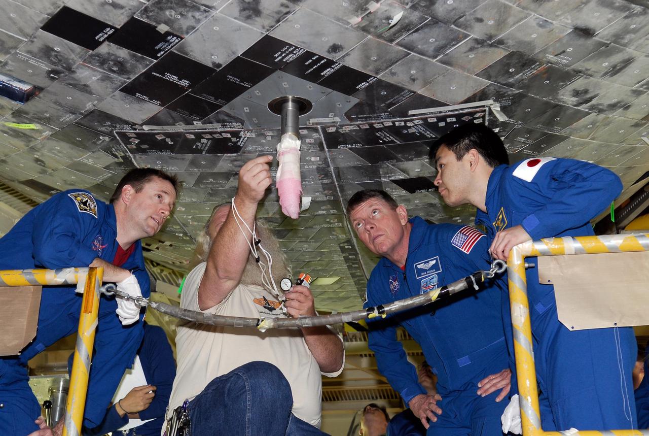 KENNEDY SPACE CENTER, FLA. -- During a crew equipment interface test in the Orbiter Processing Facility bay 3 at NASA's Kennedy Space Center, members of the STS-124 crew, along with a technician, get a close look at the underside of space shuttle Discovery and the attach point for the external tank. The crew members from left are Pilot Kenneth Ham and Mission Specialists Michael Fossum and Akihiko Hoshide, who represents the Japan Aerospace Exploration Agency, called JAXA. On the mission, Discovery will transport the Kibo Japanese Experiment Module - Pressurized Module (JEM-PM) and the Japanese Remote Manipulator System (JEM-RMS) to the International Space Station to complete the Kibo laboratory. The launch of Discovery is targeted for April 24. Photo credit: NASA/Kim Shiflett