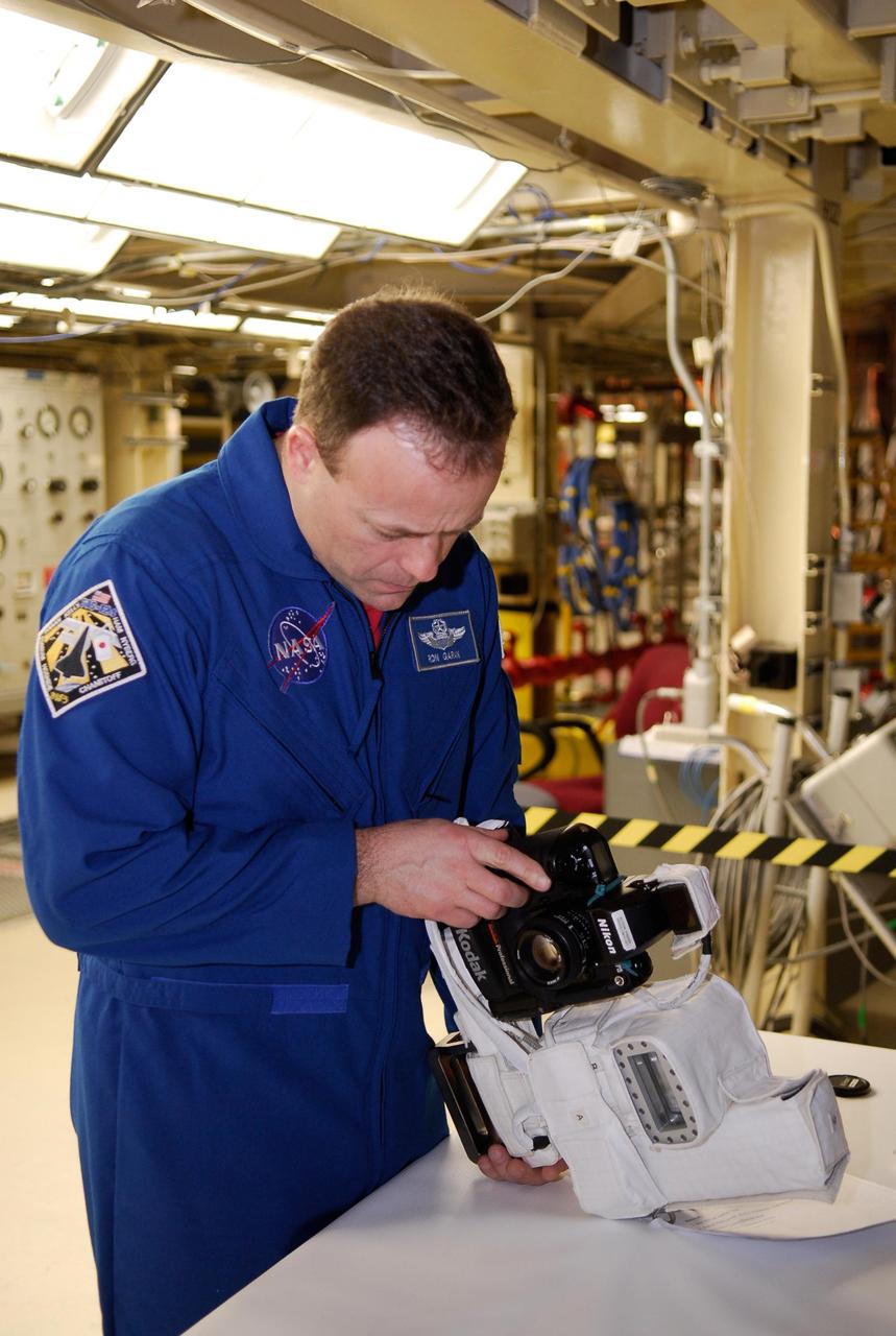 KENNEDY SPACE CENTER, FLA. -- During a crew equipment interface test in the Orbiter Processing Facility bay 3 at NASA's Kennedy Space Center, STS-124 Mission Specialist Ronald Garan inspects a camera that will be used on the mission. Space shuttle Discovery will transport the Kibo Japanese Experiment Module - Pressurized Module (JEM-PM) and the Japanese Remote Manipulator System (JEM-RMS) to the International Space Station to complete the Kibo laboratory. The launch of Discovery is targeted for April 24. Photo credit: NASA/Kim Shiflett
