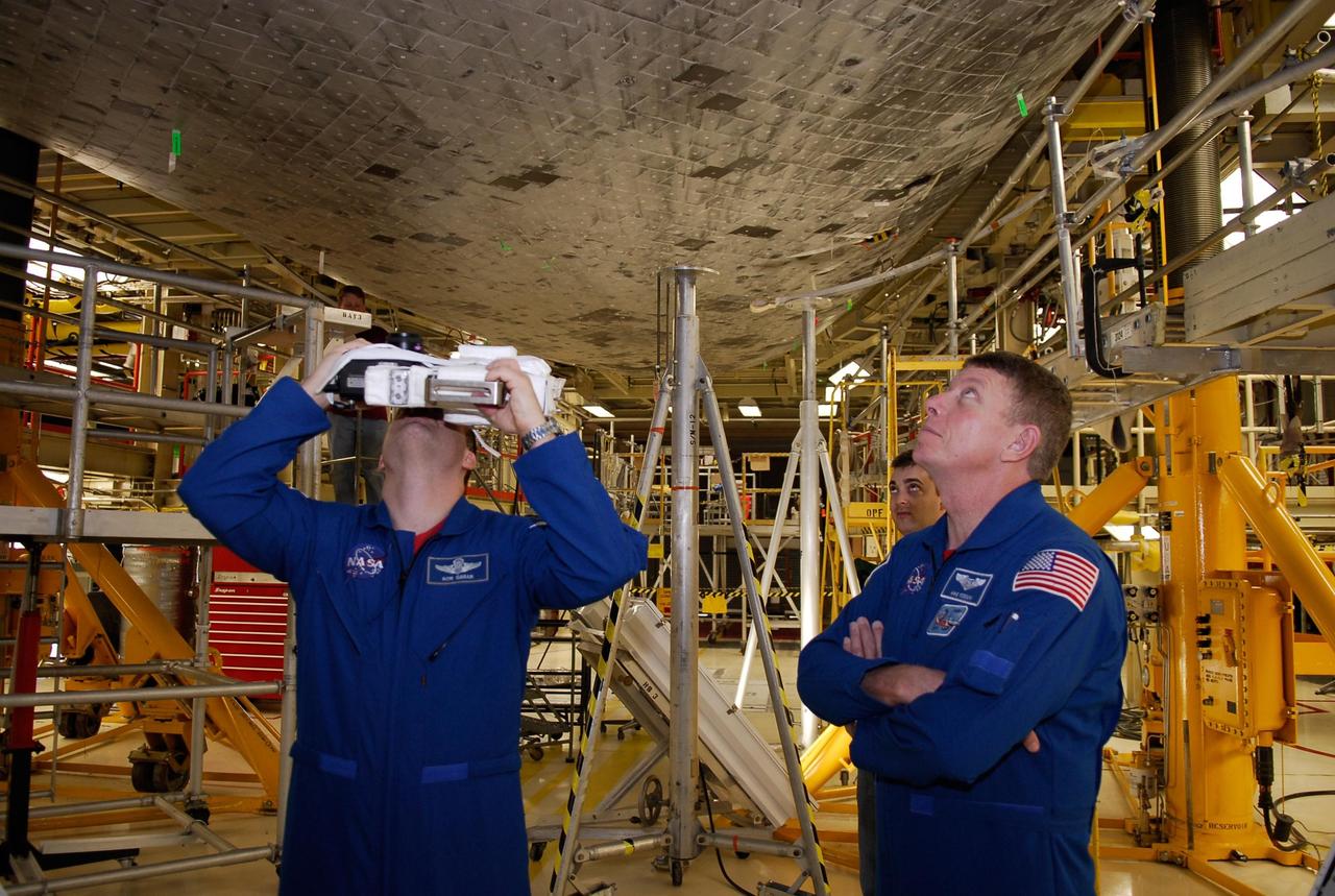 KENNEDY SPACE CENTER, FLA. -- During a crew equipment interface test in the Orbiter Processing Facility bay 3 at NASA's Kennedy Space Center, STS-124 Mission Specialist Ronald Garan practices focusing a camera on the underside of space shuttle Discovery. At right is Mission Specialist Michael Fossum. The camera will be used on the mission. Discovery will transport the Kibo Japanese Experiment Module - Pressurized Module (JEM-PM) and the Japanese Remote Manipulator System (JEM-RMS) to the International Space Station to complete the Kibo laboratory. The launch of Discovery is targeted for April 24. Photo credit: NASA/Kim Shiflett