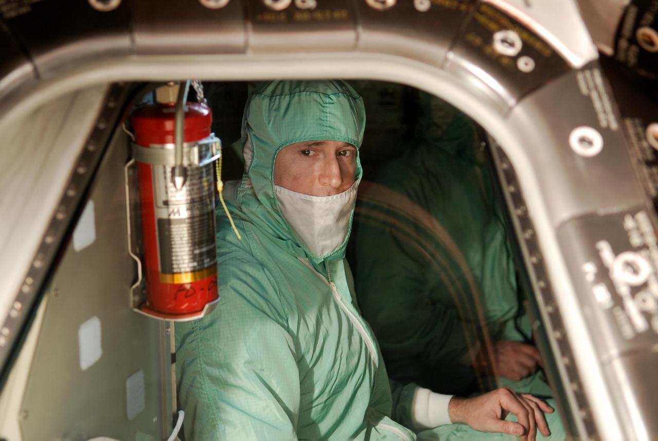 KENNEDY SPACE CENTER, FLA. -- During a crew equipment interface test in the Orbiter Processing Facility bay 3 at NASA's Kennedy Space Center, STS-124 Pilot Kenneth Ham examines the area around his seat in the cockpit of space shuttle Discovery. The shuttle will transport the Kibo Japanese Experiment Module - Pressurized Module (JEM-PM) and the Japanese Remote Manipulator System (JEM-RMS) to the International Space Station to complete the Kibo laboratory.  The launch of Discovery is targeted for April 24.  Photo credit: NASA/Kim Shiflett