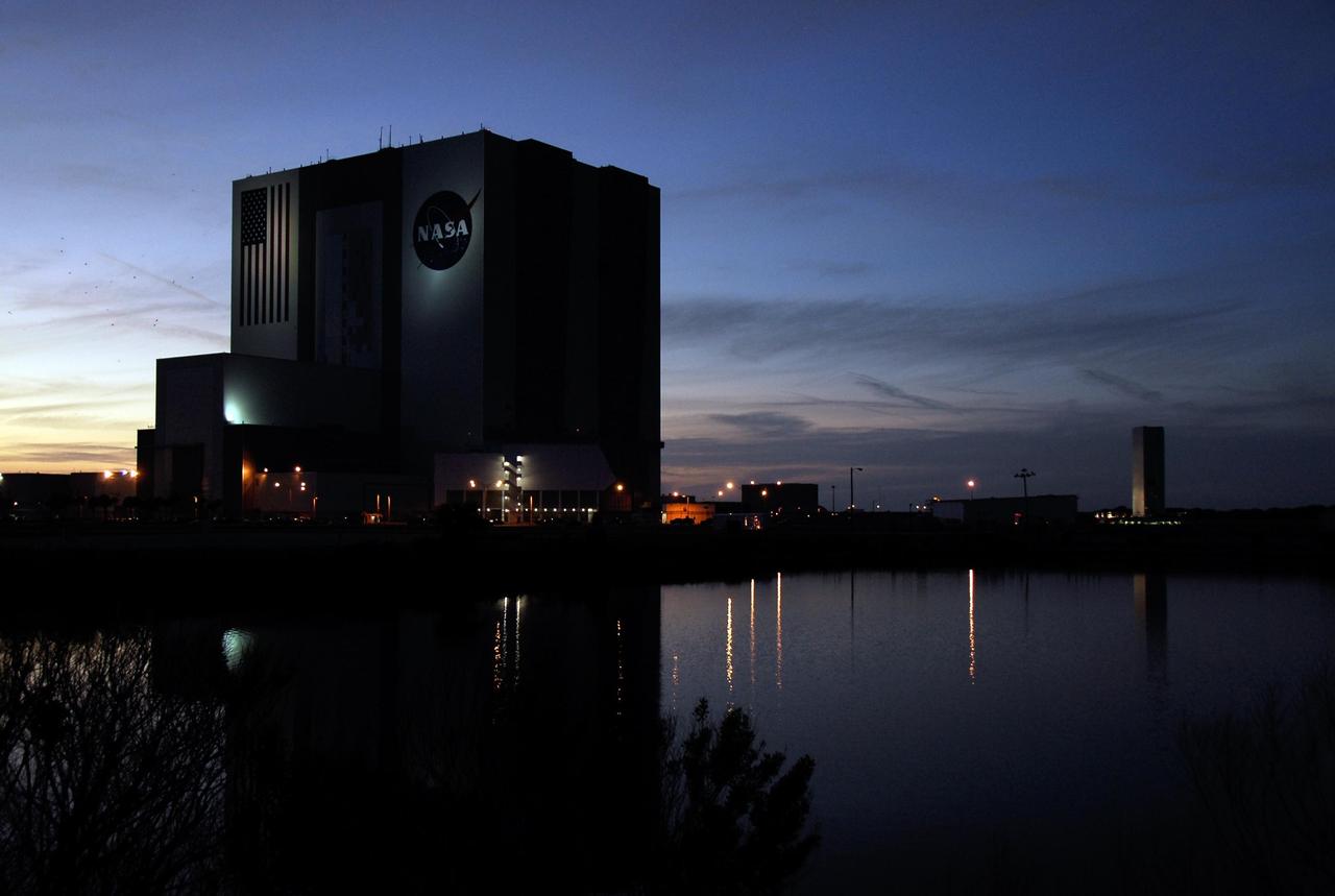 KENNEDY SPACE CENTER, FLA. --  Under a darkening sky, the payload canister (center, far right) containing the first section of the Japan Aerospace Exploration Agency's Kibo laboratory and the Canadian Space Agency's two-armed robotic system, Dextre, slowly moves toward Launch Pad 39A at NASA's Kennedy Space Center.  At the pad the payload will be transferred to the payload changeout room, part of the rotating service structure. The changeout room is the enclosed, environmentally controlled portion of the rotating service structure that supports cargo delivery to the pad and subsequent vertical installation into an orbiter's payload bay.  The payload will be installed into Endeavour for launch on the STS-123 mission targeted for March 11.  Photo credit: NASA/Kim Shiflett