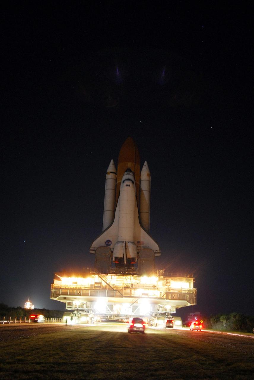 KENNEDY SPACE CENTER, FLA. -- Brilliant lights illuminate the mobile launcher platform and crawler transporter as space shuttle Endeavour makes its way to Launch Pad 39A for the STS-123 mission. At left, the launch pad glows against the night sky. The journey from the Vehicle Assembly Building began at 11:24 p.m. on Feb. 17, approximately 30 minutes before it's scheduled start time due to favorable weather conditions. The shuttle arrived at the launch pad at 4:45 a.m. Monday and was hard down at 6:22 a.m. On the mission, Endeavour and its crew will deliver the first section of the Japan Aerospace Exploration Agency's Kibo laboratory and the Canadian Space Agency's two-armed robotic system, Dextre. Launch is targeted for March 11. Photo credit: NASA/Amanda Diller