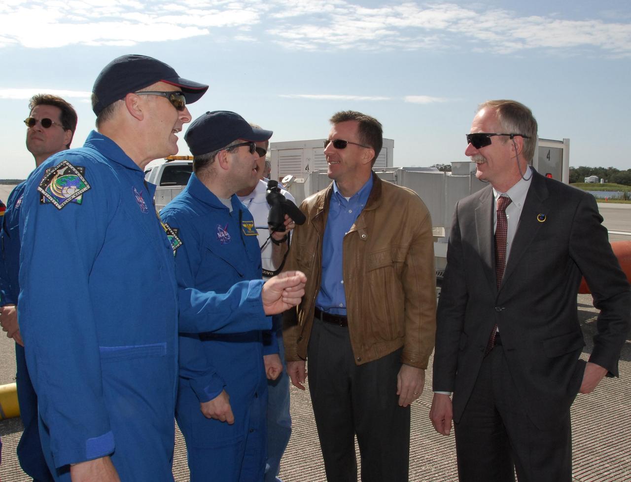 KENNEDY SPACE CENTER, FLA. --  After exiting the crew transport vehicle, STS-122 Pilot Alan Poindexter (left) and Commander Steve Frick talk to Director of Mission Launch Integration LeRoy Cain and NASA Associate Administrator for Space Operations William Gerstenmaier.  After a round trip of nearly 5.3 million miles, space shuttle Atlantis and crew returned to Earth with a landing at 9:07 a.m. EST. The shuttle landed on orbit 202 to complete the 13-day STS-122 mission. Main gear touchdown was 9:07:10 a.m. Nose gear touchdown was 9:07:20 a.m. Wheel stop was at 9:08:08 a.m. Mission elapsed time was 12 days, 18 hours, 21 minutes and 44 seconds. During the mission, Atlantis' crew installed the new Columbus laboratory, leaving a larger space station and one with increased science capabilities. The Columbus Research Module adds nearly 1,000 cubic feet of habitable volume and affords room for 10 experiment racks, each an independent science lab. Photo credit: NASA/Jack Pfaller
