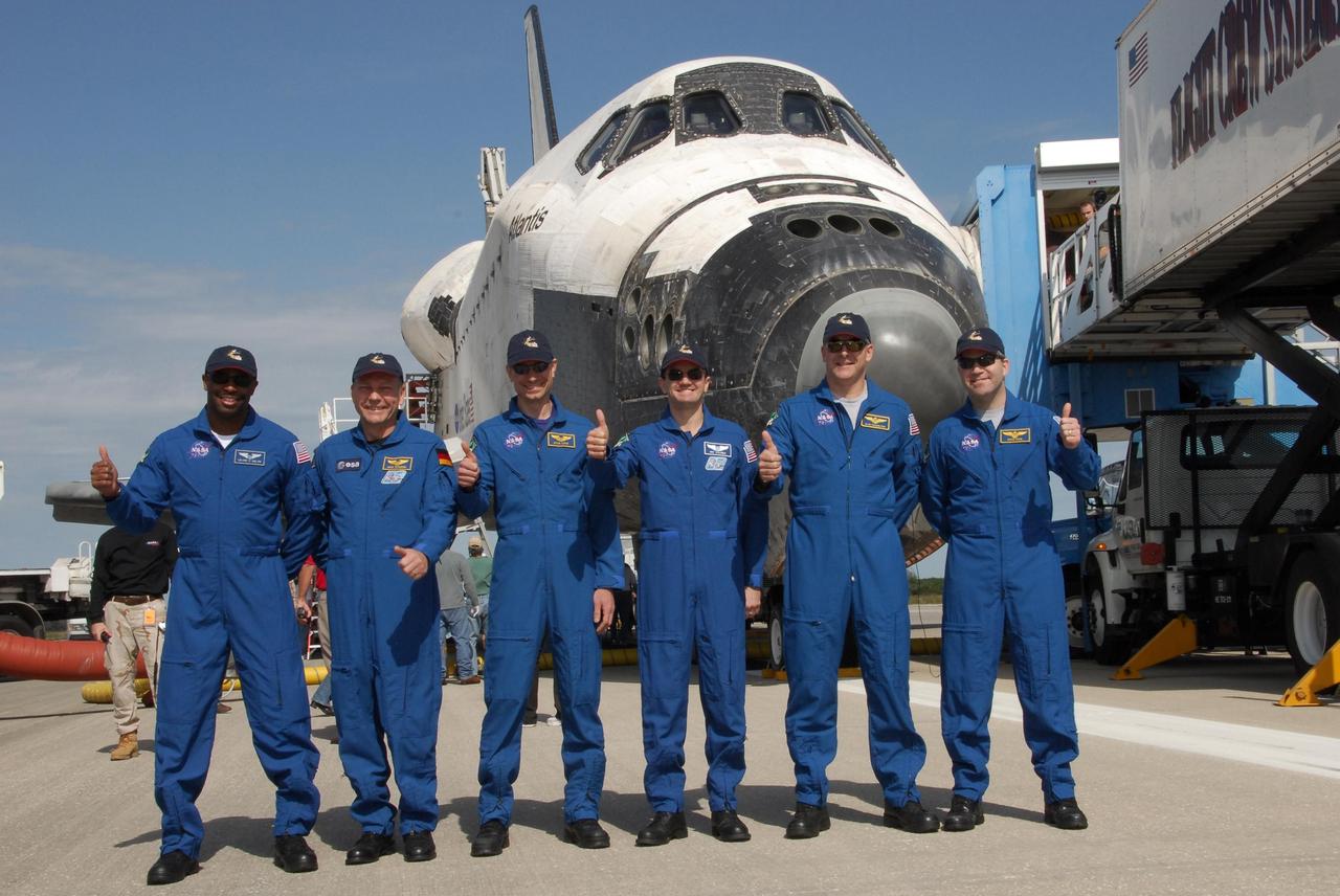 KENNEDY SPACE CENTER, FLA. --  After greeting the media on the Shuttle Landing Facility at NASA's Kennedy Space Center, the STS-122 crew signals a successful mission and landing.  From left are Mission Specialists Leland Melvin, Hans Schlegel, Rex Walheim  and Stanley Love, Pilot Alan Poindexter and Commander Steve Frick.  Schlegel represents the European Space Agency.  After a round trip of nearly 5.3 million miles, space shuttle Atlantis and crew returned to Earth with a landing at 9:07 a.m. EST. The shuttle landed on orbit 202 to complete the 13-day STS-122 mission. Main gear touchdown was 9:07:10 a.m. Nose gear touchdown was 9:07:20 a.m. Wheel stop was at 9:08:08 a.m. Mission elapsed time was 12 days, 18 hours, 21 minutes and 44 seconds. During the mission, Atlantis' crew installed the new Columbus laboratory, leaving a larger space station and one with increased science capabilities. The Columbus Research Module adds nearly 1,000 cubic feet of habitable volume and affords room for 10 experiment racks, each an independent science lab. Photo credit: NASA/Jack Pfaller