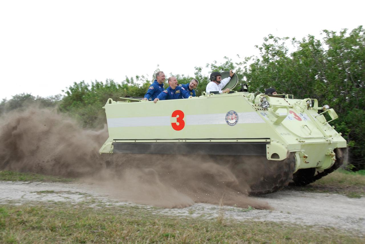 KENNEDY SPACE CENTER, FLA. -- At NASA Kennedy Space Center's Launch Complex 39, astronaut rescue team leader Capt. George Hoggard, in the white sweatshirt, demonstrates to members of the crew for space shuttle Endeavour's STS-123 mission the speed at which an M-113 armored personnel carrier can travel.  From left are Commander Dominic Gorie and Mission Specialists Garrett Reisman and Rick Linnehan.  The entire crew will practice driving the M-113 as part of his training on emergency egress procedures.  An M-113 will be available to transport the crew to safety in the event of a contingency on the pad before their launch.  The STS-123 crew is at Kennedy for a full launch dress rehearsal, known as the terminal countdown demonstration test or TCDT.  Endeavour's seven astronauts arrived at Kennedy's Shuttle Landing Facility in their T-38 training aircraft between 10:45 and 10:58 a.m. EST. The terminal countdown demonstration test provides astronauts and ground crews with an opportunity to participate in various simulated countdown activities, including equipment familiarization and emergency training. Endeavour is targeted to launch March 11 at 2:28 a.m. EDT on a 16-day mission to the International Space Station. On the mission, Endeavour and its crew will deliver the first section of the Japan Aerospace Exploration Agency's Kibo laboratory and the Canadian Space Agency's two-armed robotic system, Dextre. Photo credit: NASA/Kim Shiflett