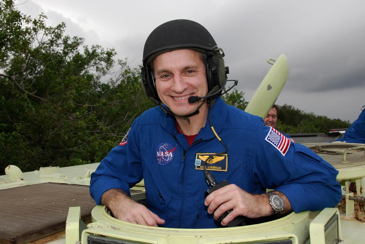 KENNEDY SPACE CENTER, FLA. -- At NASA Kennedy Space Center's Launch Complex 39, STS-123 Mission Specialist Rick Linnehan takes time out from driving practice of the M-113 armored personnel carrier to pose for a photo.  The crew members of space shuttle Endeavour's STS-123 mission will each practice driving the M-113 in turn as part of his training on emergency egress procedures.  An M-113 will be available to transport the crew to safety in the event of a contingency on the pad before their launch.  The STS-123 crew is at Kennedy for a full launch dress rehearsal, known as the terminal countdown demonstration test or TCDT.  Endeavour's seven astronauts arrived at Kennedy's Shuttle Landing Facility in their T-38 training aircraft between 10:45 and 10:58 a.m. EST. The terminal countdown demonstration test provides astronauts and ground crews with an opportunity to participate in various simulated countdown activities, including equipment familiarization and emergency training. Endeavour is targeted to launch March 11 at 2:28 a.m. EDT on a 16-day mission to the International Space Station. On the mission, Endeavour and its crew will deliver the first section of the Japan Aerospace Exploration Agency's Kibo laboratory and the Canadian Space Agency's two-armed robotic system, Dextre. Photo credit: NASA/Kim Shiflett