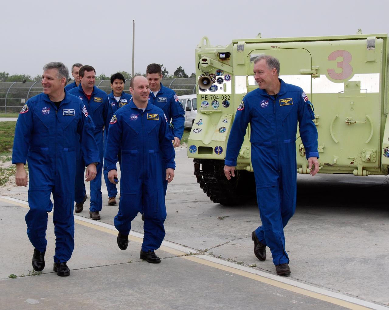 KENNEDY SPACE CENTER, FLA. -- At NASA Kennedy Space Center's Launch Pad 39A, the crew for space shuttle Endeavour's STS-123 mission walks past an M-113 armored personnel carrier on their way to answer questions from the media. From left, in the front row are Pilot Gregory H. Johnson, Mission Specialist Garrett Reisman and Commander Dominic Gorie. In the middle row are Mission Specialists Mike Foreman and Robert L. Behnken. In the back row are Mission Specialists Rick Linnehan and Takao Doi of the Japan Aerospace Exploration Agency. The crew is at Kennedy for a full launch dress rehearsal, known as the terminal countdown demonstration test or TCDT. The terminal countdown demonstration test provides astronauts and ground crews with an opportunity to participate in various simulated countdown activities, including equipment familiarization and emergency training. Endeavour is targeted to launch March 11 at 2:28 a.m. EDT on a 16-day mission to the International Space Station. On the mission, Endeavour and its crew will deliver the first section of the Japan Aerospace Exploration Agency's Kibo laboratory and the Canadian Space Agency's two-armed robotic system, Dextre. Photo credit: NASA/Kim Shiflett