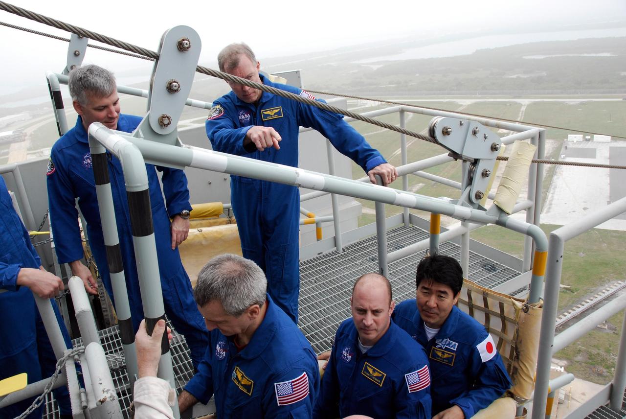 KENNEDY SPACE CENTER, FLA. -- At NASA Kennedy Space Center's Launch Pad 39A, the crew for space shuttle Endeavour's STS-123 mission receives instruction on the operation of a slidewire basket during emergency egress training. From top left are Pilot Gregory H. Johnson and Commander Dominic Gorie. In the basket are Mission Specialists Rick Linnehan, Garrett Reisman and Takao Doi of the Japan Aerospace Exploration Agency. The crew is at Kennedy for a full launch dress rehearsal, known as the terminal countdown demonstration test or TCDT. The terminal countdown demonstration test provides astronauts and ground crews with an opportunity to participate in various simulated countdown activities, including equipment familiarization and emergency training. Endeavour is targeted to launch March 11 at 2:28 a.m. EDT on a 16-day mission to the International Space Station. On the mission, Endeavour and its crew will deliver the first section of the Japan Aerospace Exploration Agency's Kibo laboratory and the Canadian Space Agency's two-armed robotic system, Dextre. Photo credit: NASA/Kim Shiflett