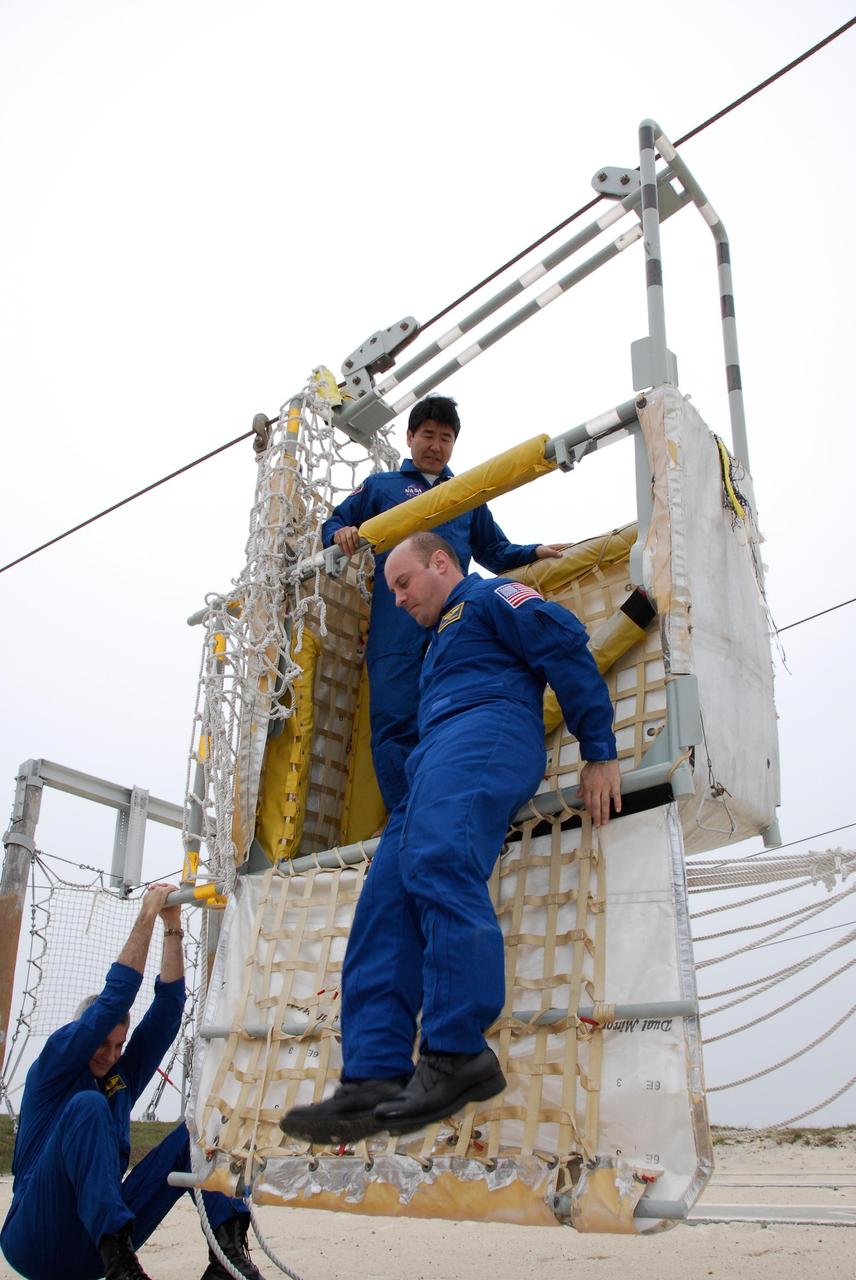 KENNEDY SPACE CENTER, FLA. -- At NASA Kennedy Space Center's Launch Pad 39A, the crew for space shuttle Endeavour's STS-123 mission receives instruction on the operation of a slidewire basket during emergency egress training. Mission Specialist Takao Doi of the Japan Aerospace Exploration Agency observes from the basket as Mission Specialist Rick Linnehan steadies the basket for Mission Specialist Garrett Reisman to jump to the ground. The crew is at Kennedy for a full launch dress rehearsal, known as the terminal countdown demonstration test or TCDT. The terminal countdown demonstration test provides astronauts and ground crews with an opportunity to participate in various simulated countdown activities, including equipment familiarization and emergency training. Endeavour is targeted to launch March 11 at 2:28 a.m. EDT on a 16-day mission to the International Space Station. On the mission, Endeavour and its crew will deliver the first section of the Japan Aerospace Exploration Agency's Kibo laboratory and the Canadian Space Agency's two-armed robotic system, Dextre. Photo credit: NASA/Kim Shiflett