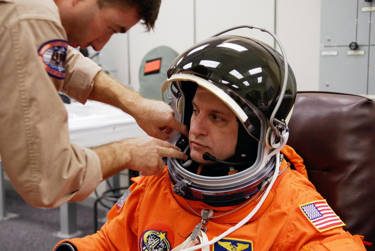 KENNEDY SPACE CENTER, FLA. --   STS-123 Mission Specialist Garrett Reisman is helped with his helmet while suiting up for the launch dress rehearsal, culmination of the terminal countdown demonstration test, or TCDT. The TCDT provides astronauts and ground crews with an opportunity to participate in various simulated countdown activities, including equipment familiarization and emergency training. Space shuttle Endeavour is targeted to launch March 11 at 2:28 a.m. EDT on the 16-day STS-123 mission to the International Space Station.  Endeavour and its crew will deliver the first section of the Japan Aerospace Exploration Agency's Kibo laboratory and the Canadian Space Agency's two-armed robotic system, Dextre.   Photo credit: NASA/Kim Shiflett