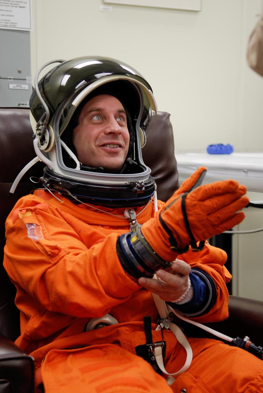 KENNEDY SPACE CENTER, FLA. --   STS-123 Mission Specialist Garrett Reisman works at putting on his gloves while suiting up for the launch dress rehearsal, culmination of the terminal countdown demonstration test, or TCDT.  The TCDT provides astronauts and ground crews with an opportunity to participate in various simulated countdown activities, including equipment familiarization and emergency training. Space shuttle Endeavour is targeted to launch March 11 at 2:28 a.m. EDT on the 16-day STS-123 mission to the International Space Station.  Endeavour and its crew will deliver the first section of the Japan Aerospace Exploration Agency's Kibo laboratory and the Canadian Space Agency's two-armed robotic system, Dextre.   Photo credit: NASA/Kim Shiflett
