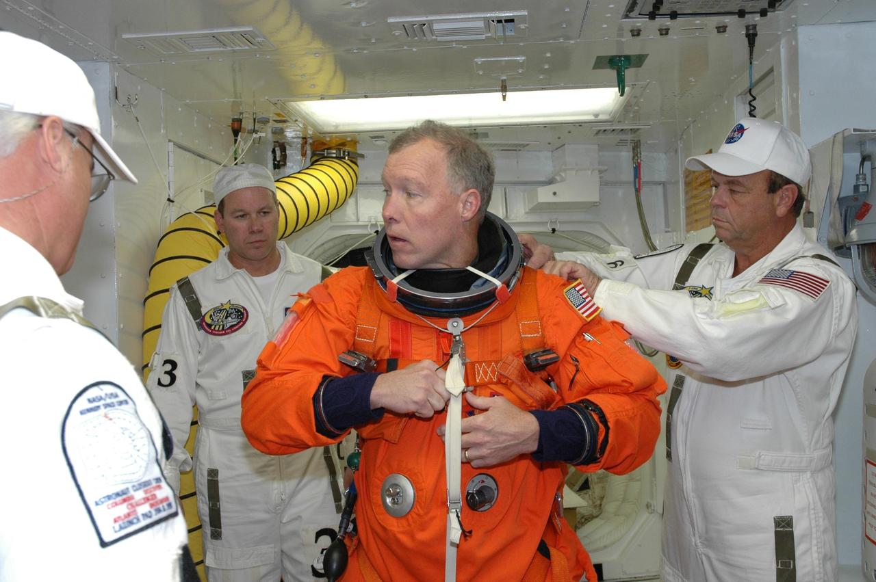 KENNEDY SPACE CENTER, FLA. --  STS-123 Commander Dominic Gorie is helped with his launch and entry suit before entering space shuttle Endeavour for the simulated launch countdown.  The countdown is the culmination of the terminal countdown demonstration test, or TCDT. The TCDT provides astronauts and ground crews with an opportunity to participate in various countdown activities, including equipment familiarization and emergency egress training. Endeavour is targeted to launch at 2:28 a.m. EDT March 11 on the 16-day STS-123 mission to the International Space Station.  Endeavour and its crew will deliver the first section of the Japan Aerospace Exploration Agency's Kibo laboratory and the Canadian Space Agency's two-armed robotic system, Dextre.   Photo credit: NASA/Jim Grossmann