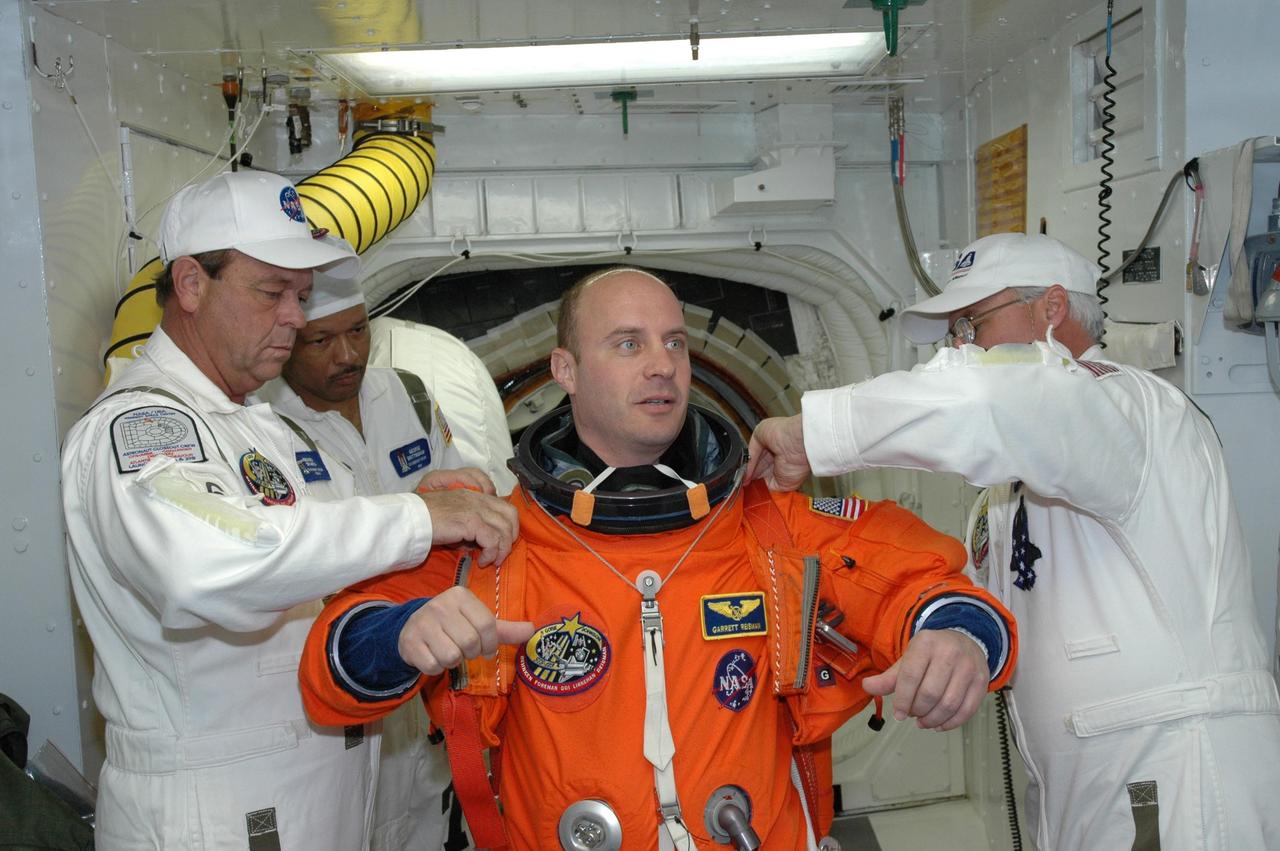 KENNEDY SPACE CENTER, FLA. --  STS-123 Mission Specialist Garrett Reisman is helped with his launch and entry suit before entering space shuttle Endeavour for the simulated launch countdown.  The countdown is the culmination of the terminal countdown demonstration test, or TCDT. The TCDT provides astronauts and ground crews with an opportunity to participate in various countdown activities, including equipment familiarization and emergency egress training. Endeavour is targeted to launch at 2:28 a.m. EDT March 11 on the 16-day STS-123 mission to the International Space Station.  Endeavour and its crew will deliver the first section of the Japan Aerospace Exploration Agency's Kibo laboratory and the Canadian Space Agency's two-armed robotic system, Dextre.   Photo credit: NASA/Jim Grossmann