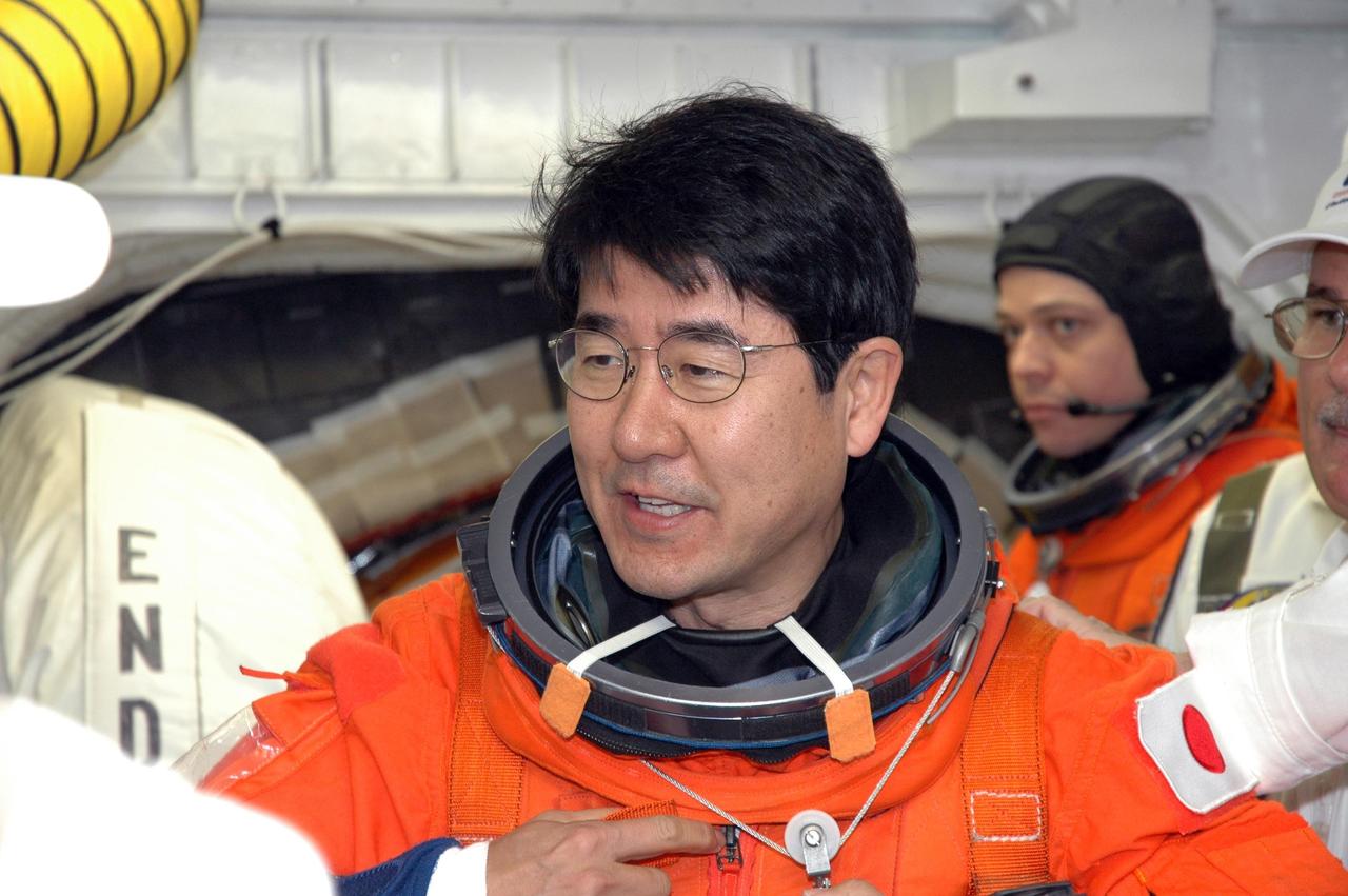 KENNEDY SPACE CENTER, FLA. -- In the White Room on NASA Kennedy Space Center's Launch Pad 39A, STS-123 Mission Specialist Takao Doi, who represents the Japan Aerospace Exploration Agency, gets help with his launch and entry suit before entering space shuttle Endeavour. He and the other STS-123 crew members are getting ready for the simulated launch countdown, which is the culmination of the terminal countdown demonstration test, or TCDT. The TCDT provides astronauts and ground crews with an opportunity to participate in various countdown activities, including equipment familiarization and emergency egress training. Endeavour is targeted to launch at 2:28 a.m. EDT March 11 on the 16-day STS-123 mission to the International Space Station. Endeavour and its crew will deliver the first section of the Japan Aerospace Exploration Agency's Kibo laboratory and the Canadian Space Agency's two-armed robotic system, Dextre. Photo credit: NASA/Jim Grossmann