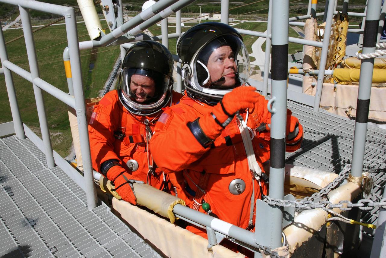 KENNEDY SPACE CENTER, FLA. -- Following the simulated launch countdown, STS-123 Mission Specialists Mike Foreman (left) and Robert L. Behnken settle in a slidewire basket on Launch Pad 39A at NASA's Kennedy Space Center.  The crew is practicing emergency egress from the pad.  The countdown was the culmination of the terminal countdown demonstration test, or TCDT. The TCDT provides astronauts and ground crews with an opportunity to participate in various countdown activities, including equipment familiarization and emergency egress training. Endeavour is targeted to launch at 2:28 a.m. EDT March 11 on the 16-day STS-123 mission to the International Space Station.  Endeavour and its crew will deliver the first section of the Japan Aerospace Exploration Agency's Kibo laboratory and the Canadian Space Agency's two-armed robotic system, Dextre.   Photo credit: NASA/Kim Shiflett