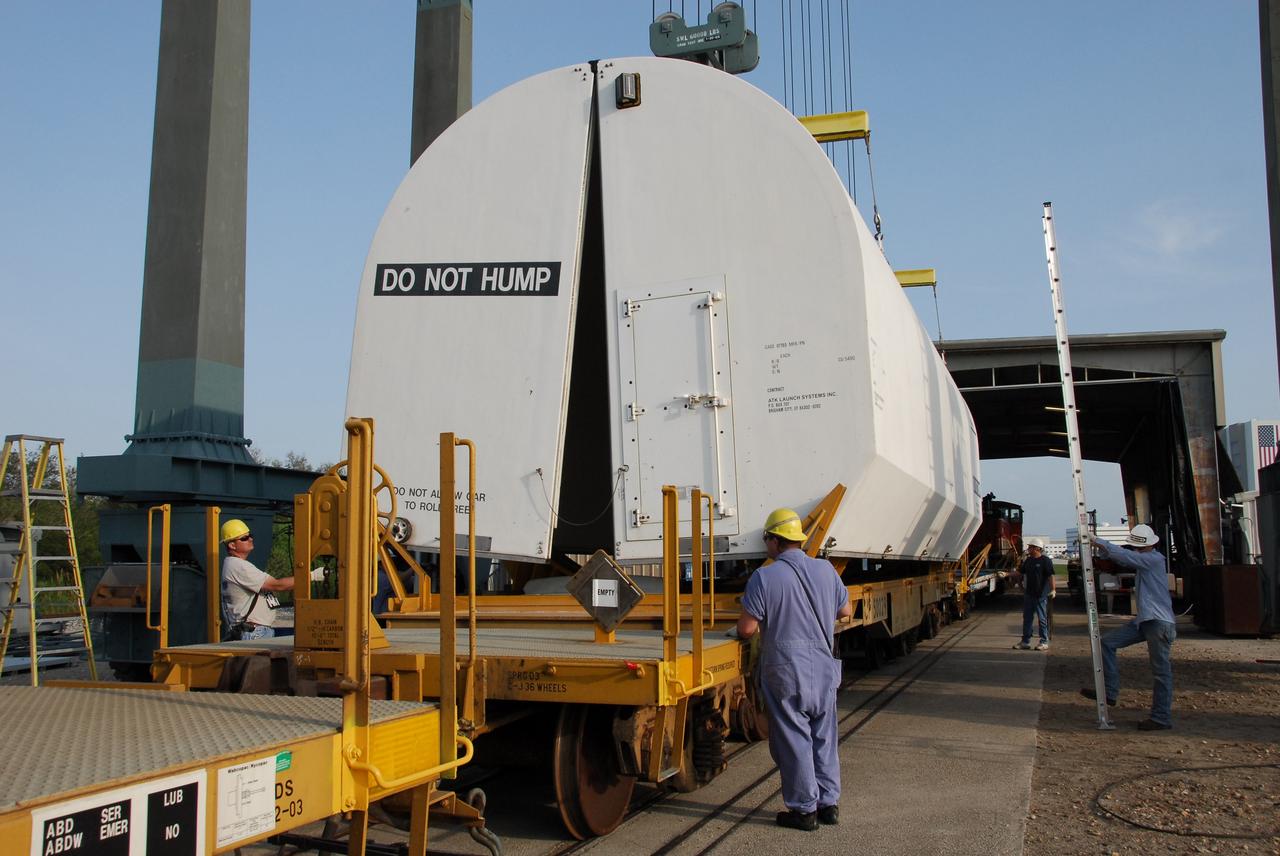 KENNEDY SPACE CENTER, FLA. --  Workers at the Railroad yard at NASA's Kennedy Space Center stand ready to secure the transportation cover over the solid rocket booster segment that is being transported to Utah. The spent segments are part of the booster used to launch space shuttle Atlantis on the STS-122 mission in February.  After a mission, the spent boosters are recovered, cleaned, disassembled, refurbished and reused after each launch. After hydrolasing the interior of each segment, they are placed on flatbed trucks. The individual booster segments are transferred to a railhead located at the railroad yard.  The covered segments will be moved to Titusville for interchange with Florida East Coast Railway to begin the trip back to the Thiokol plant in Wa¬satch, Utah.   Photo credit: NASA/Jack Pfaller